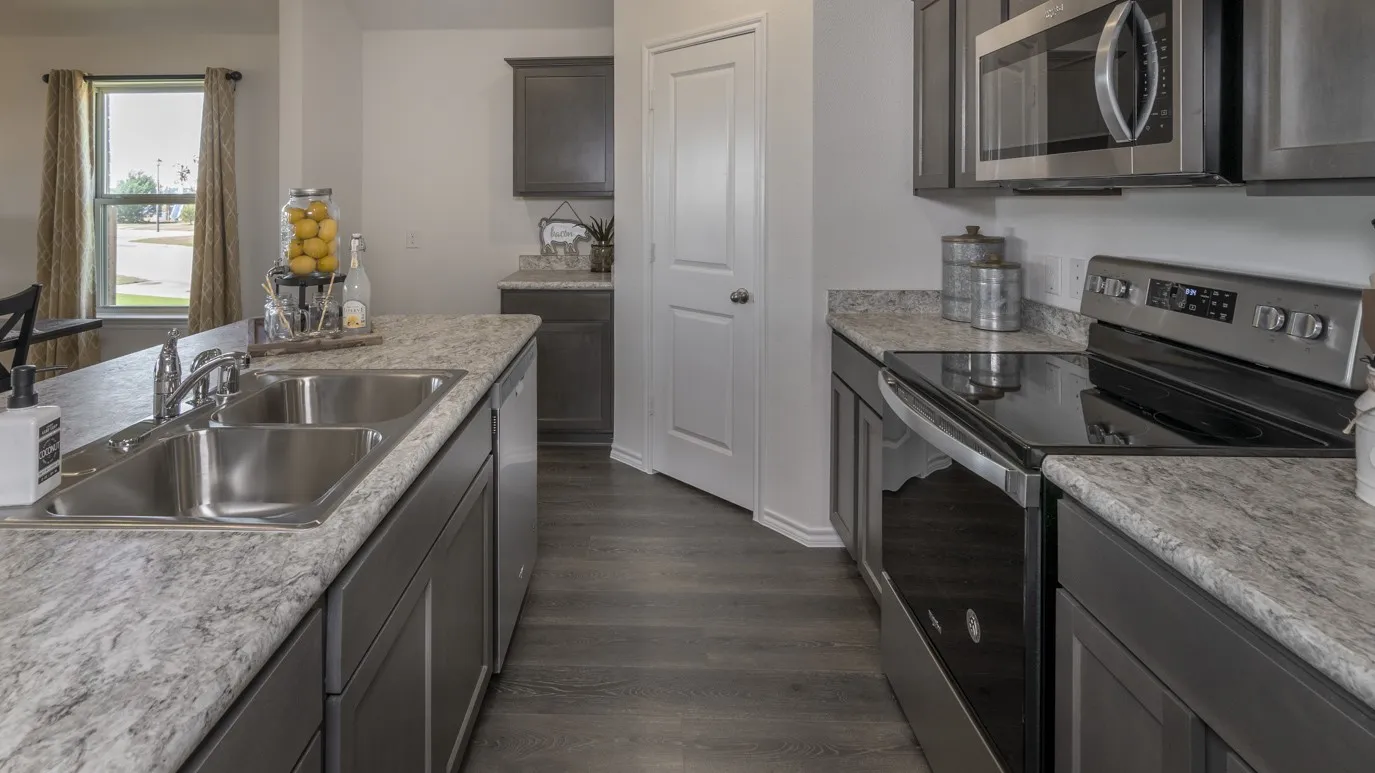 Kitchen with stainless steel appliances, light countertops, and dark wood finished floors