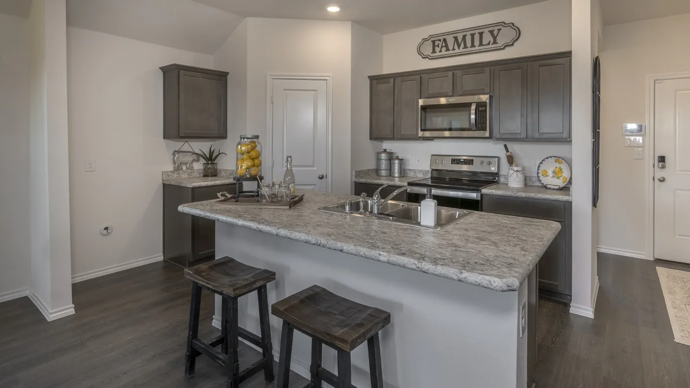 Kitchen with stainless steel appliances, light countertops, dark wood finished floors, a kitchen breakfast bar, and dark wood finish cabinetry