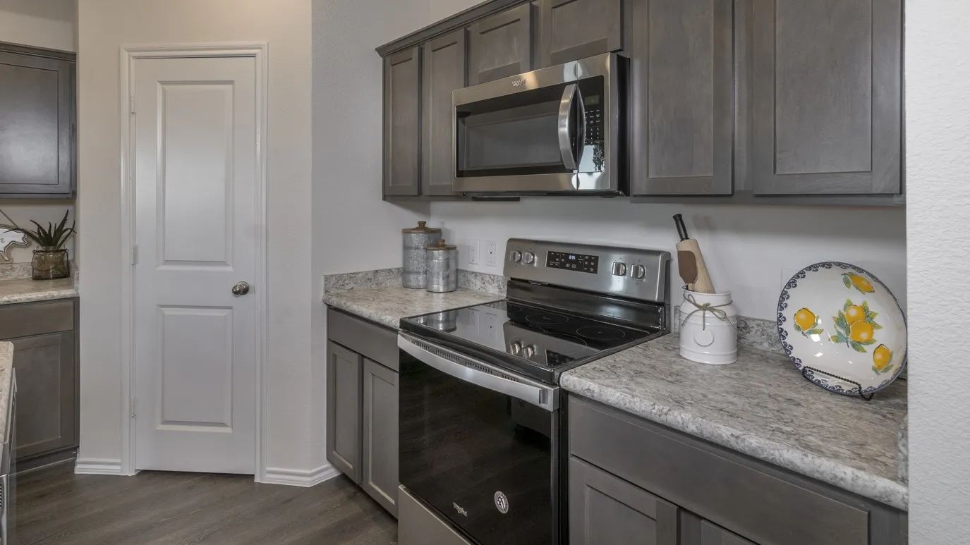 Kitchen featuring stainless steel appliances, light countertops, dark wood finished floors, and dark wood finish cabinetry
