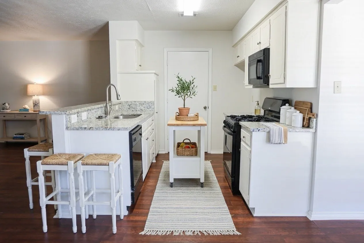 Galley kitchen featuring wood-finish flooring and white cabinetry