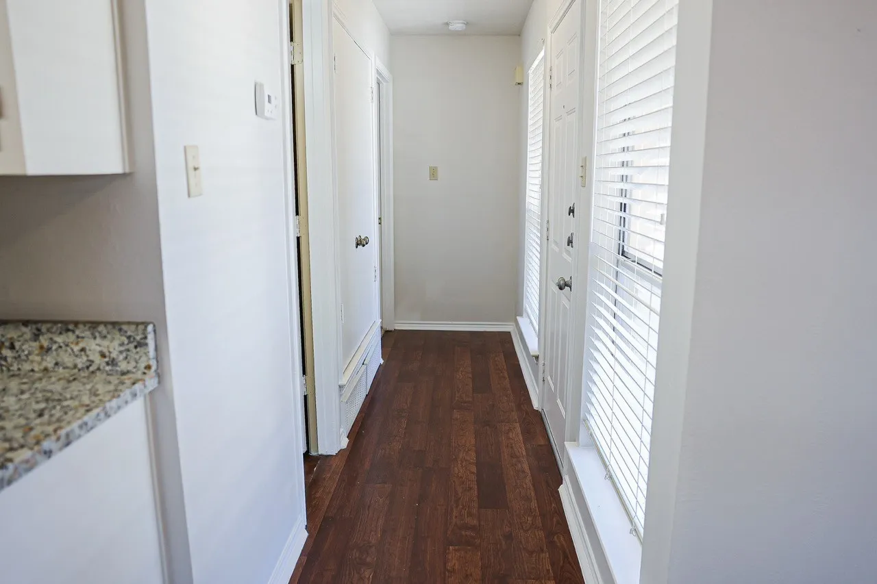 Hallway featuring wood-finish flooring, white doors, and white walls