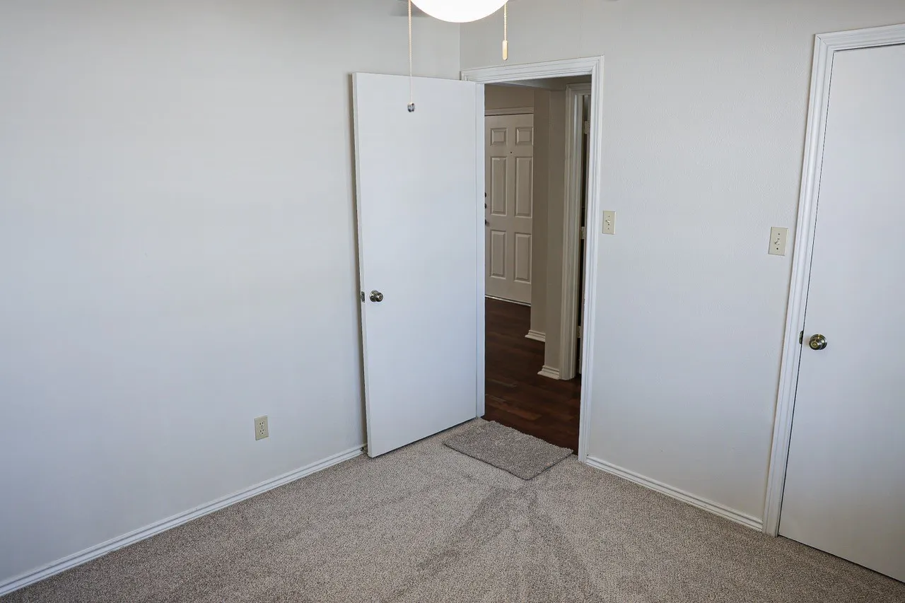 Carpeted room with white walls, white trim, and white doors