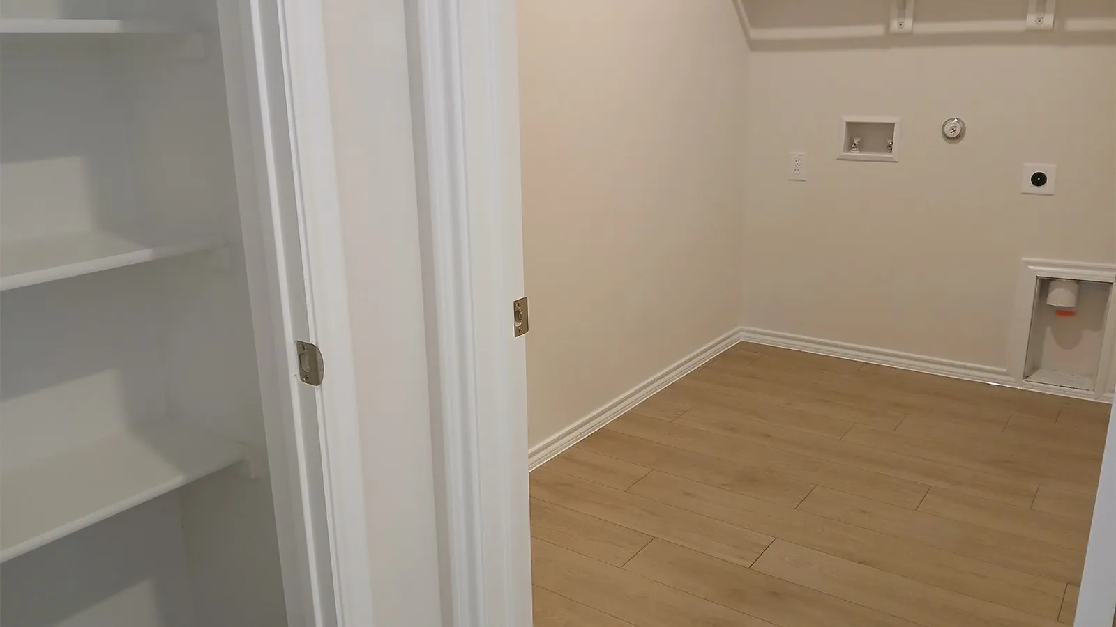 Dedicated utility space featuring wood-finish flooring, white baseboards, and neutral wall paint