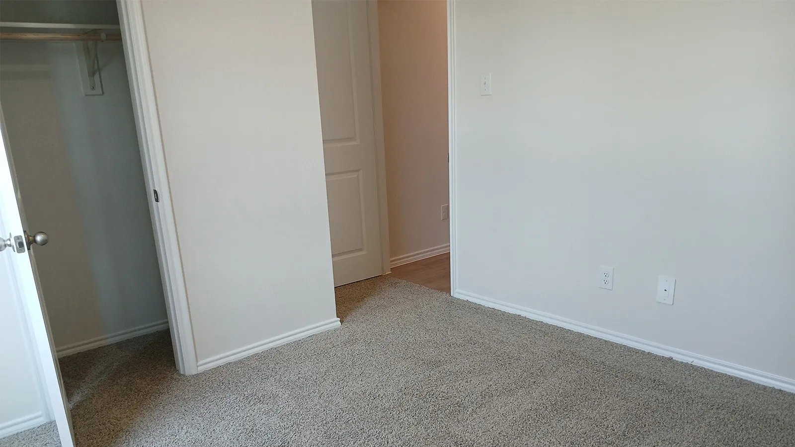 Light beige wall-to-wall carpeting throughout this space, featuring white baseboards and trim
