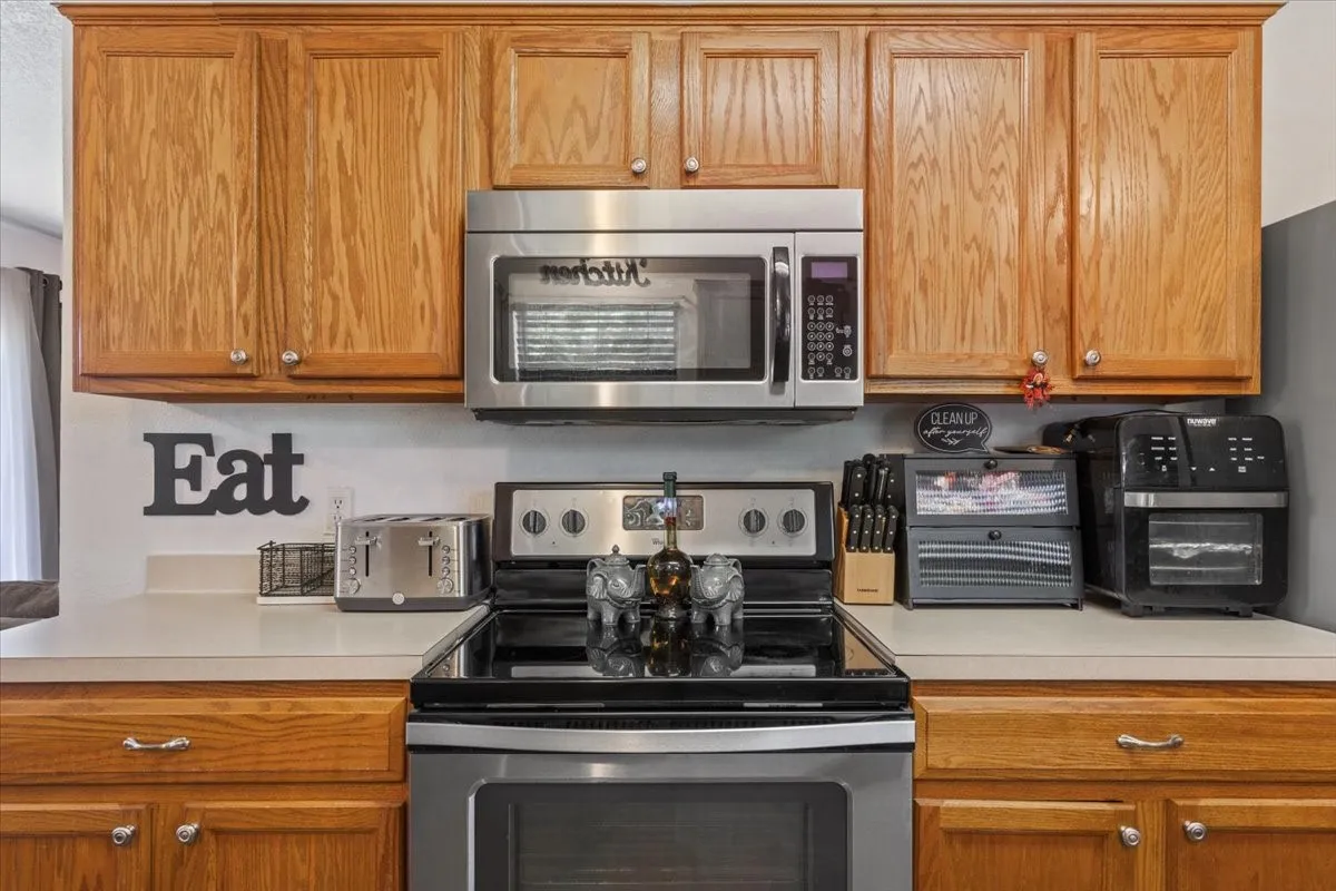 Kitchen featuring stainless steel appliances, light countertops, and wood finish cabinetry