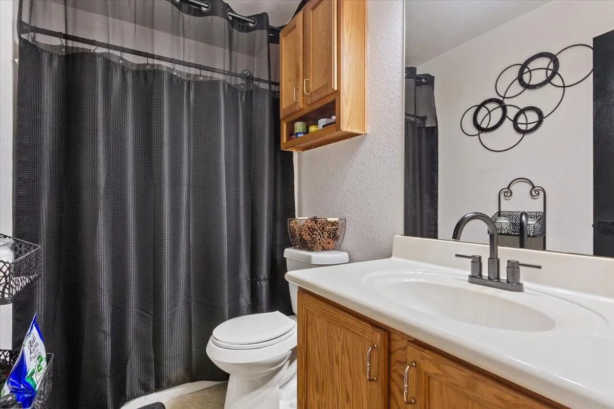 Full bath with a textured wall, vanity, and a shower with shower curtain