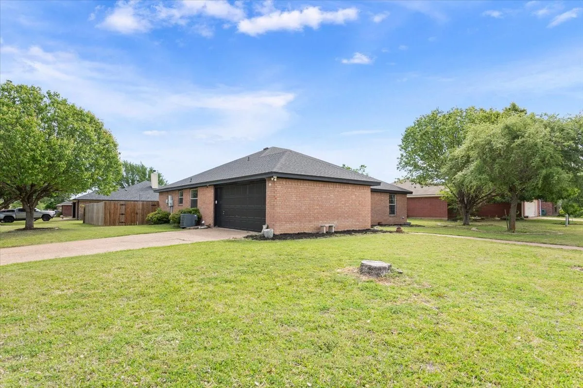View of property exterior with brick siding, driveway, and an attached garage