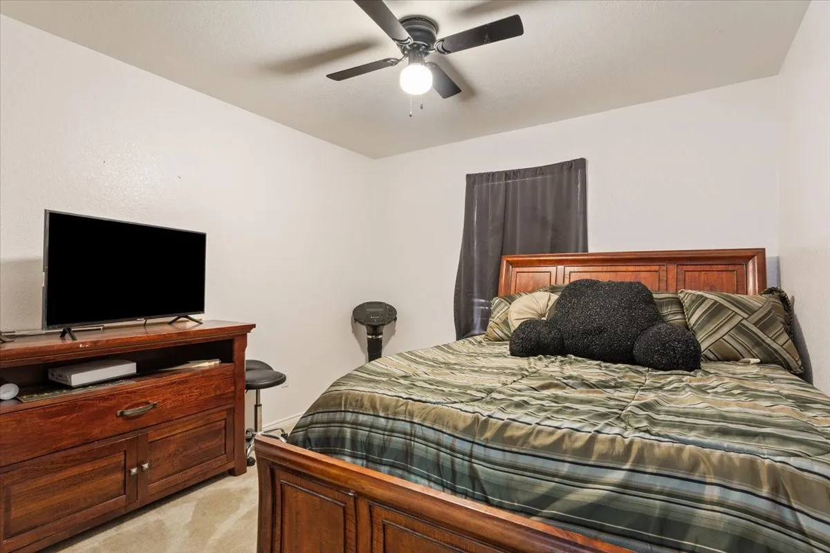 Bedroom with a ceiling fan and light colored carpet