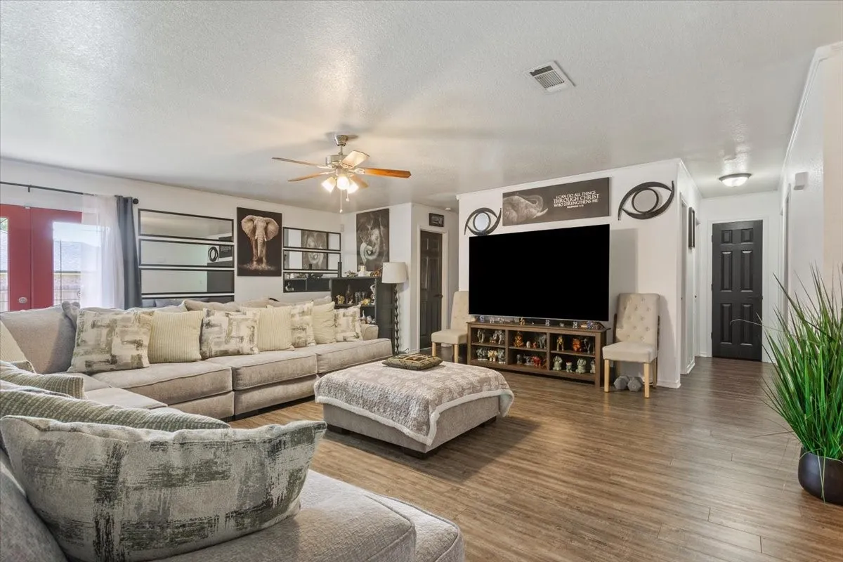 Living area with a textured ceiling, wood finished floors, and ceiling fan