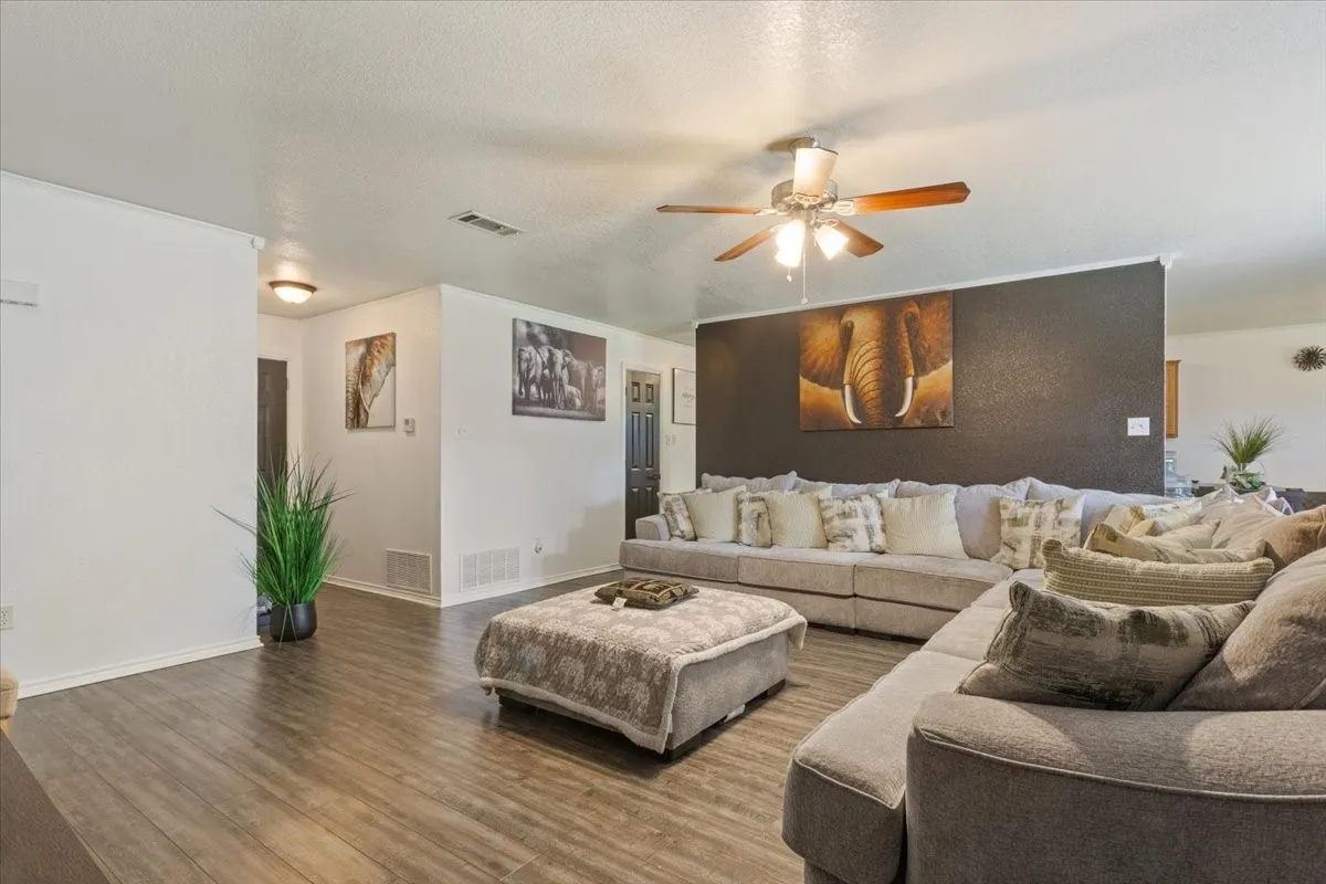 Living room featuring a ceiling fan, wood finished floors, and a textured ceiling