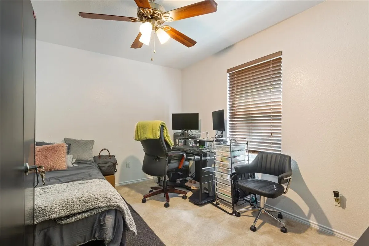 Bedroom featuring a desk, light carpet, and ceiling fan