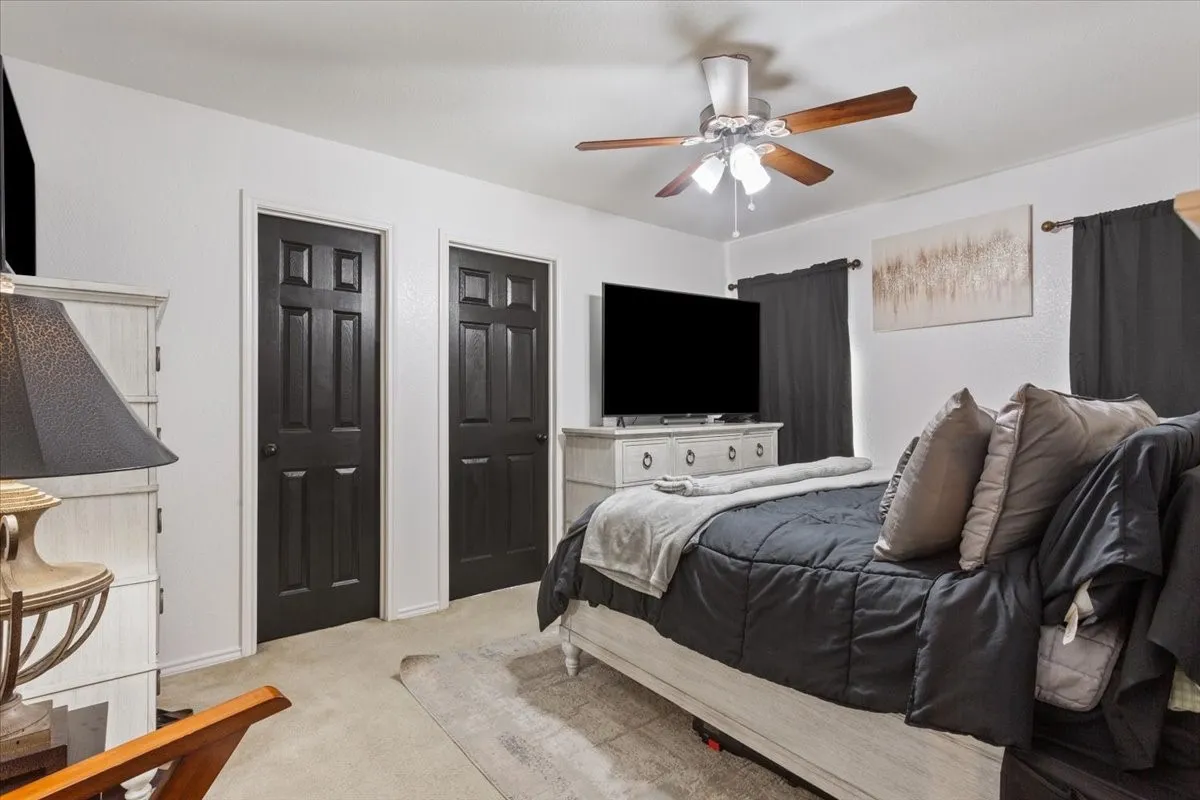 Bedroom featuring multiple closets, light carpet, and a ceiling fan