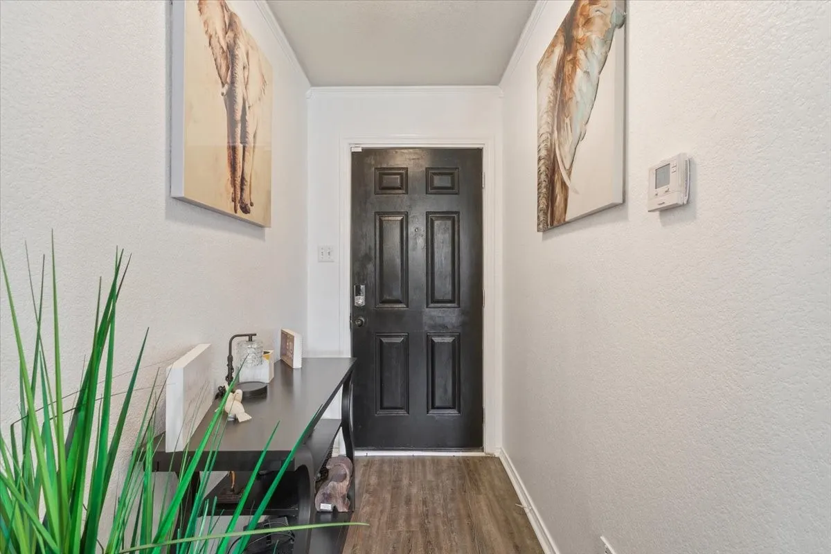Doorway to outside featuring a textured wall, wood finished floors, and ornamental molding