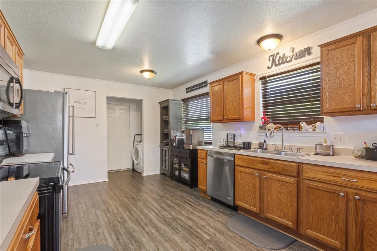 Kitchen with a textured ceiling, light countertops, wood finish cabinets, stainless steel appliances, and dark wood finished floors