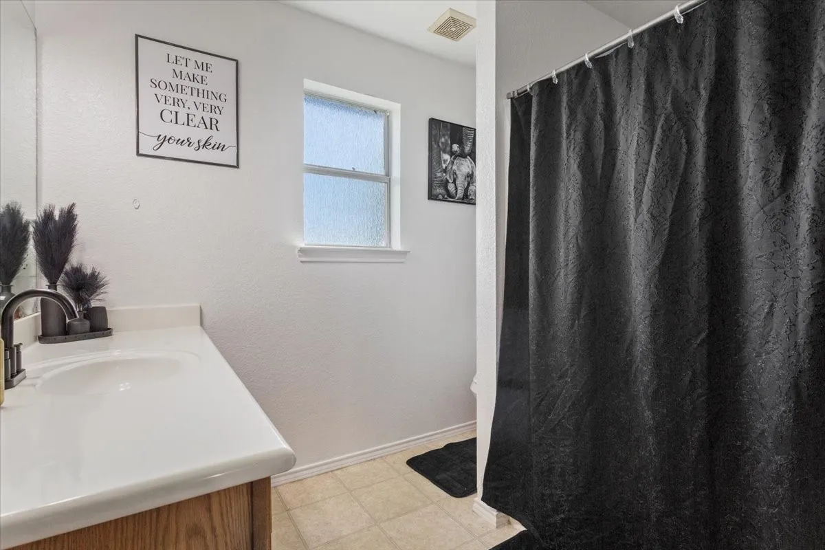 Bathroom featuring vanity, light floors, and curtained shower