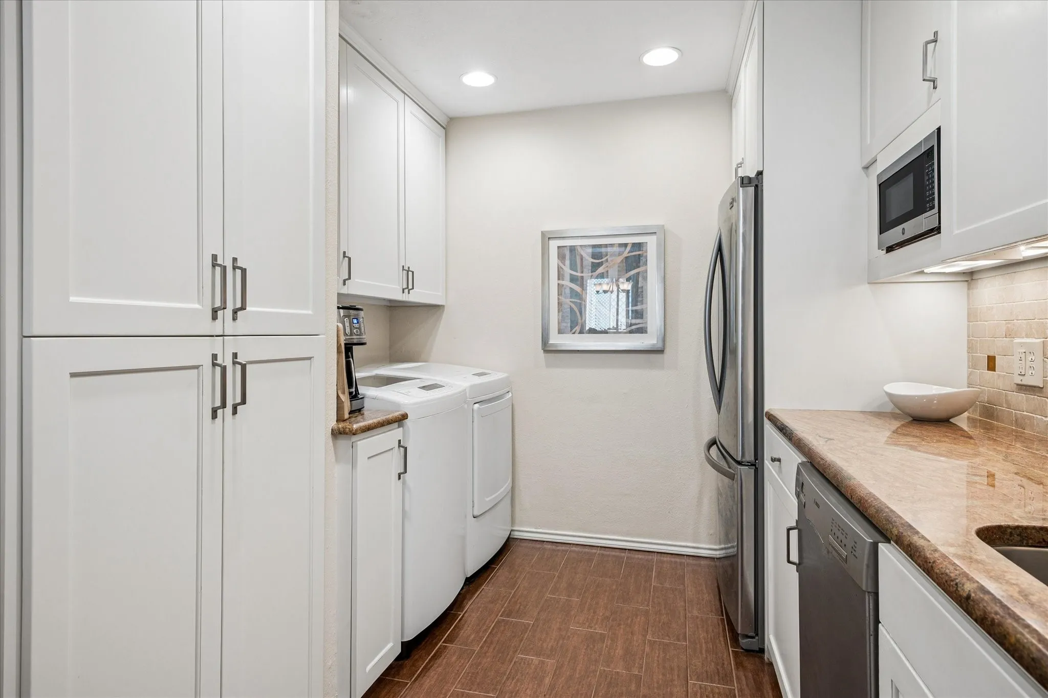 Rear view of the kitchen where you can see the pantry as well as the refrigerator and  the full size washer and dryer.
