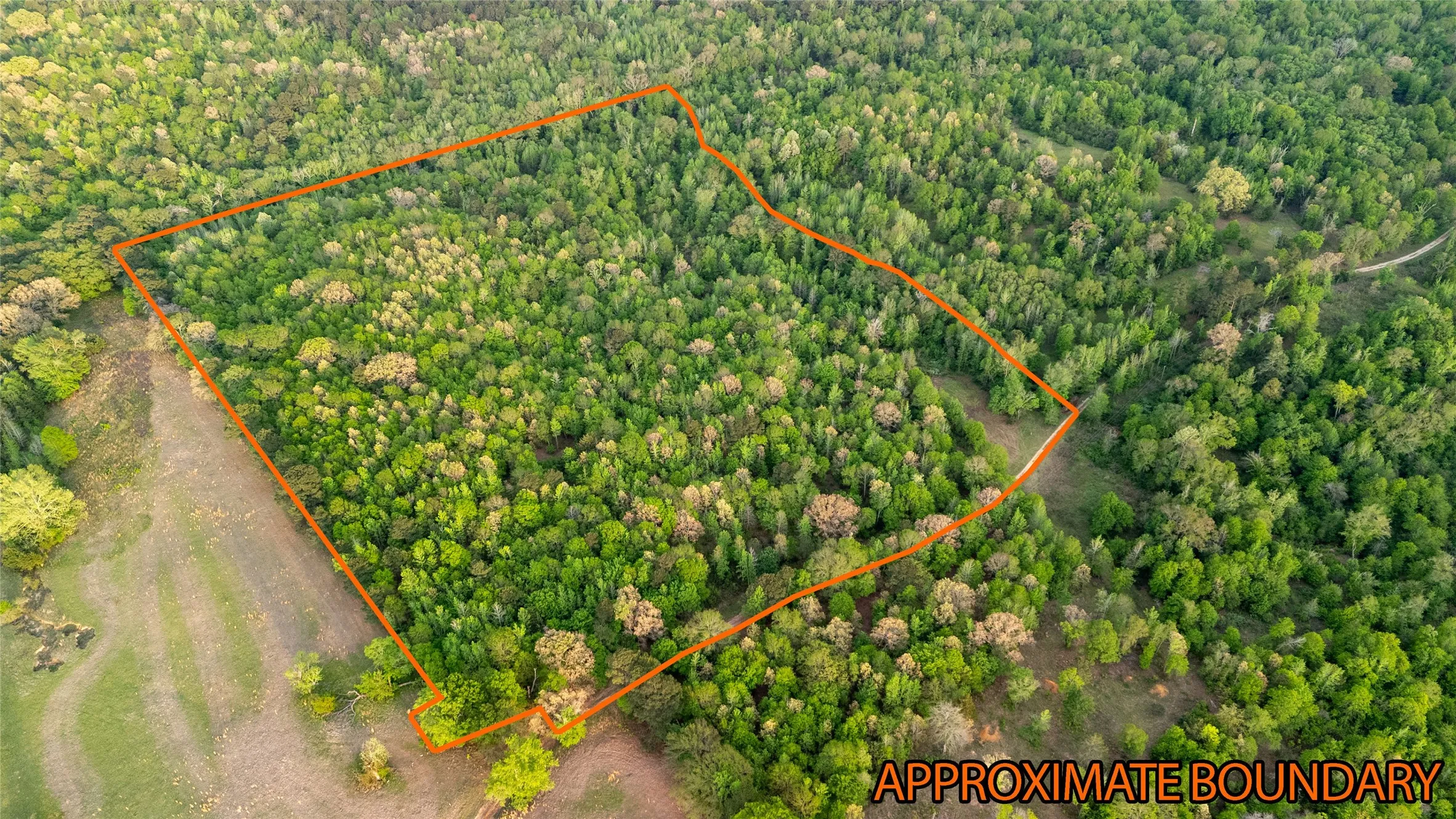 Aerial view of property's location with property parcel outlined and a heavily wooded area