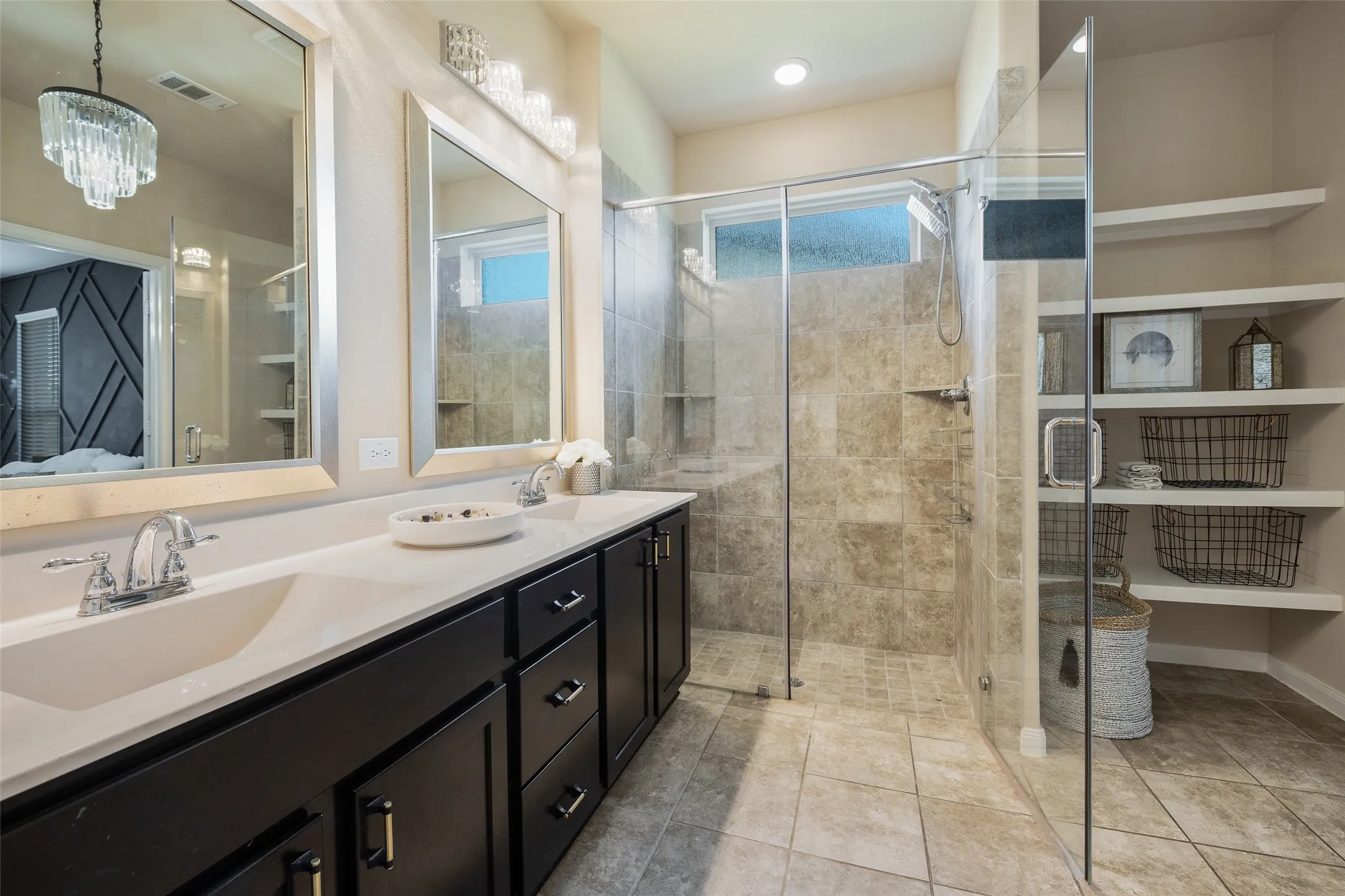 Master bathroom features dual vanities, stand up shower, elegant light fixtures, and shelving for linens