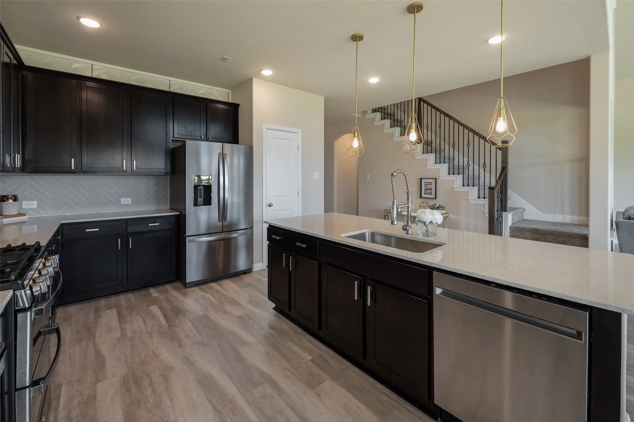 Kitchen features a gorgeous tile backsplash and designer lighting.