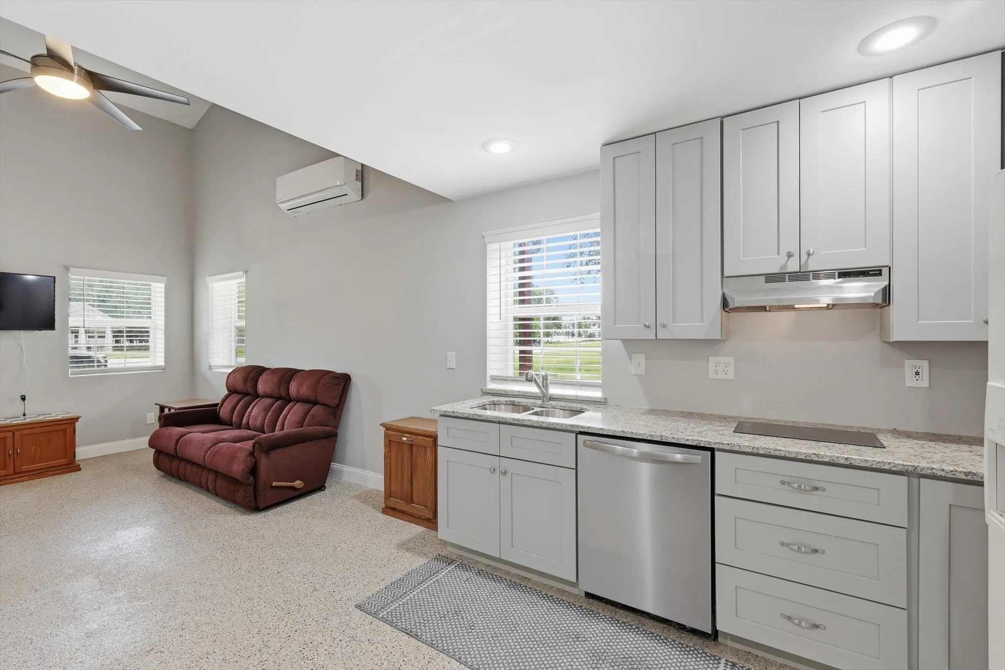 Kitchen area has granite counters, dishwasher and stovetop