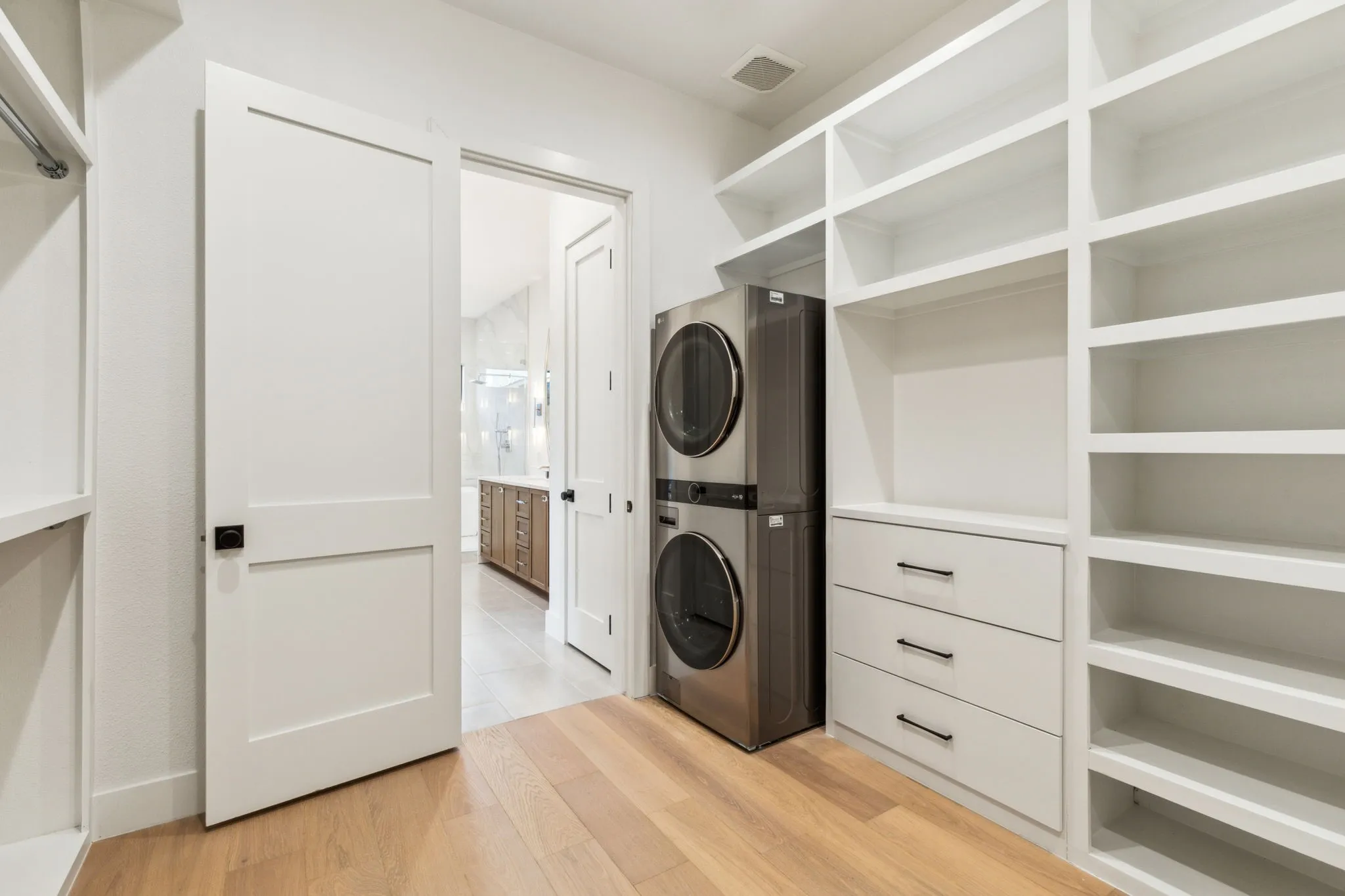Spacious primary closet with built-in shelving, drawers, and laundry area for added convenience.