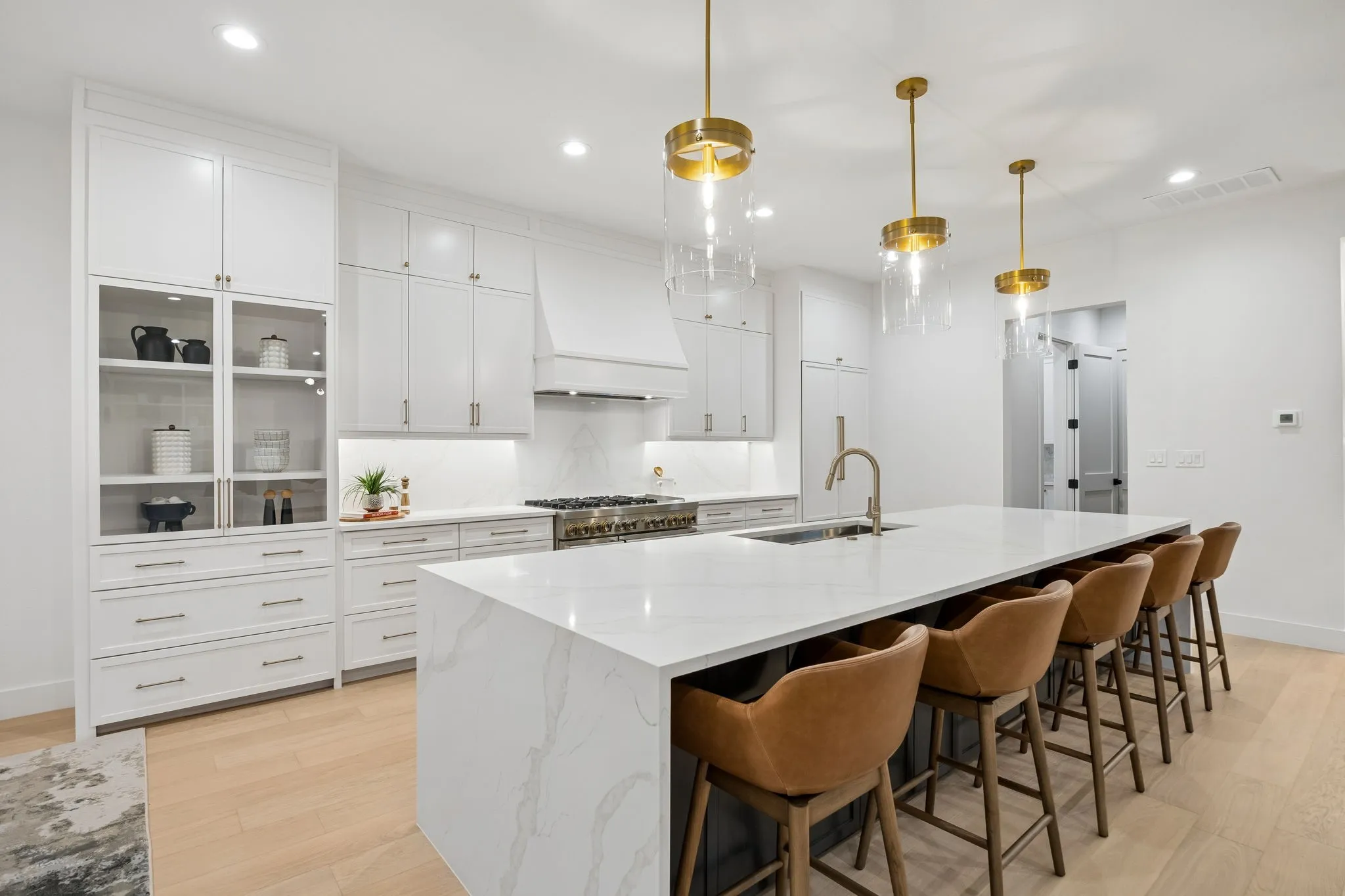 Stunning chef’s kitchen with expansive waterfall island, custom cabinetry, and premium appliances, designed for both everyday living and entertaining.