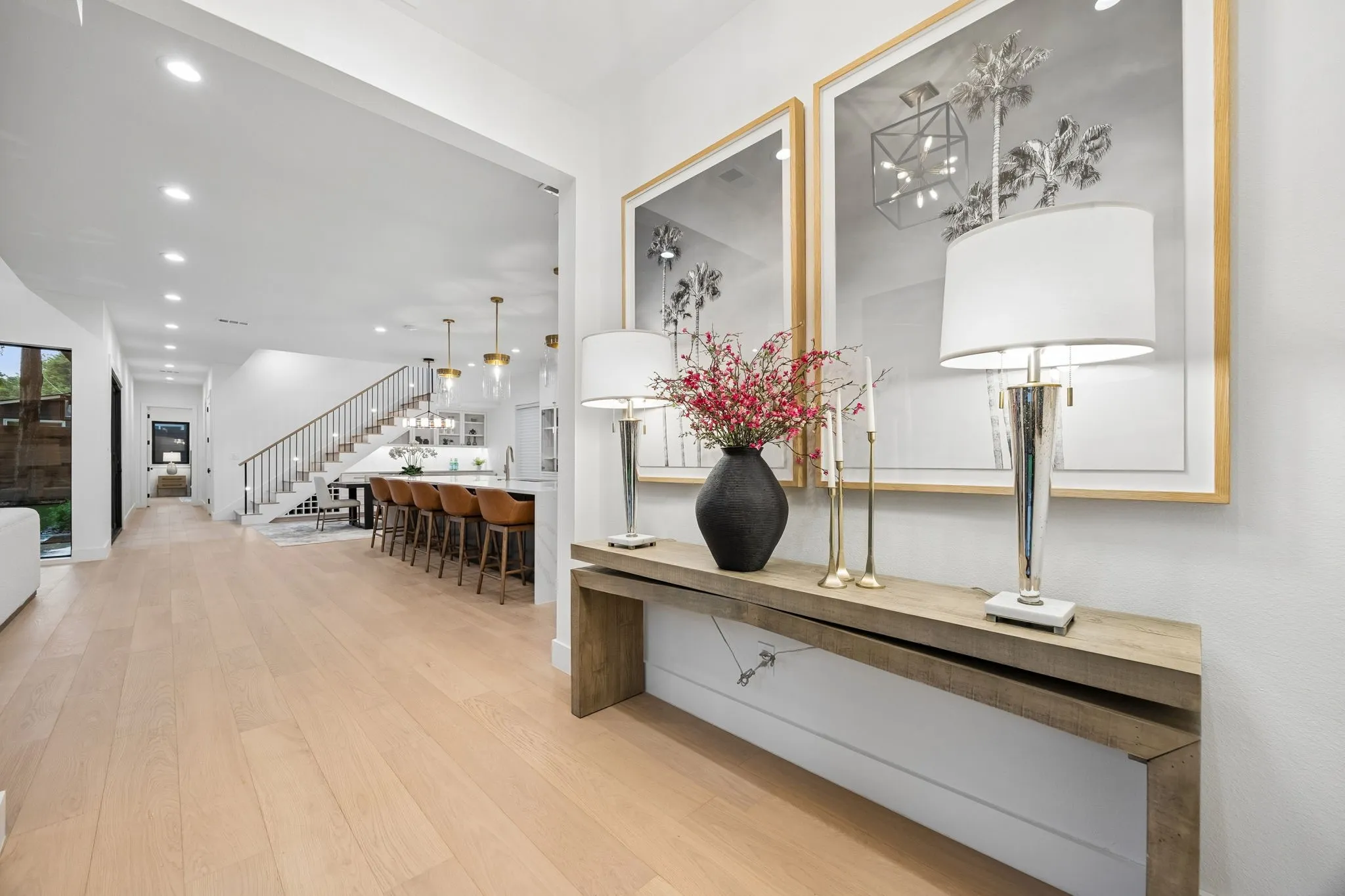Welcoming entry with designer finishes and warm wood floors, opening to a bright, open-concept living and kitchen area.