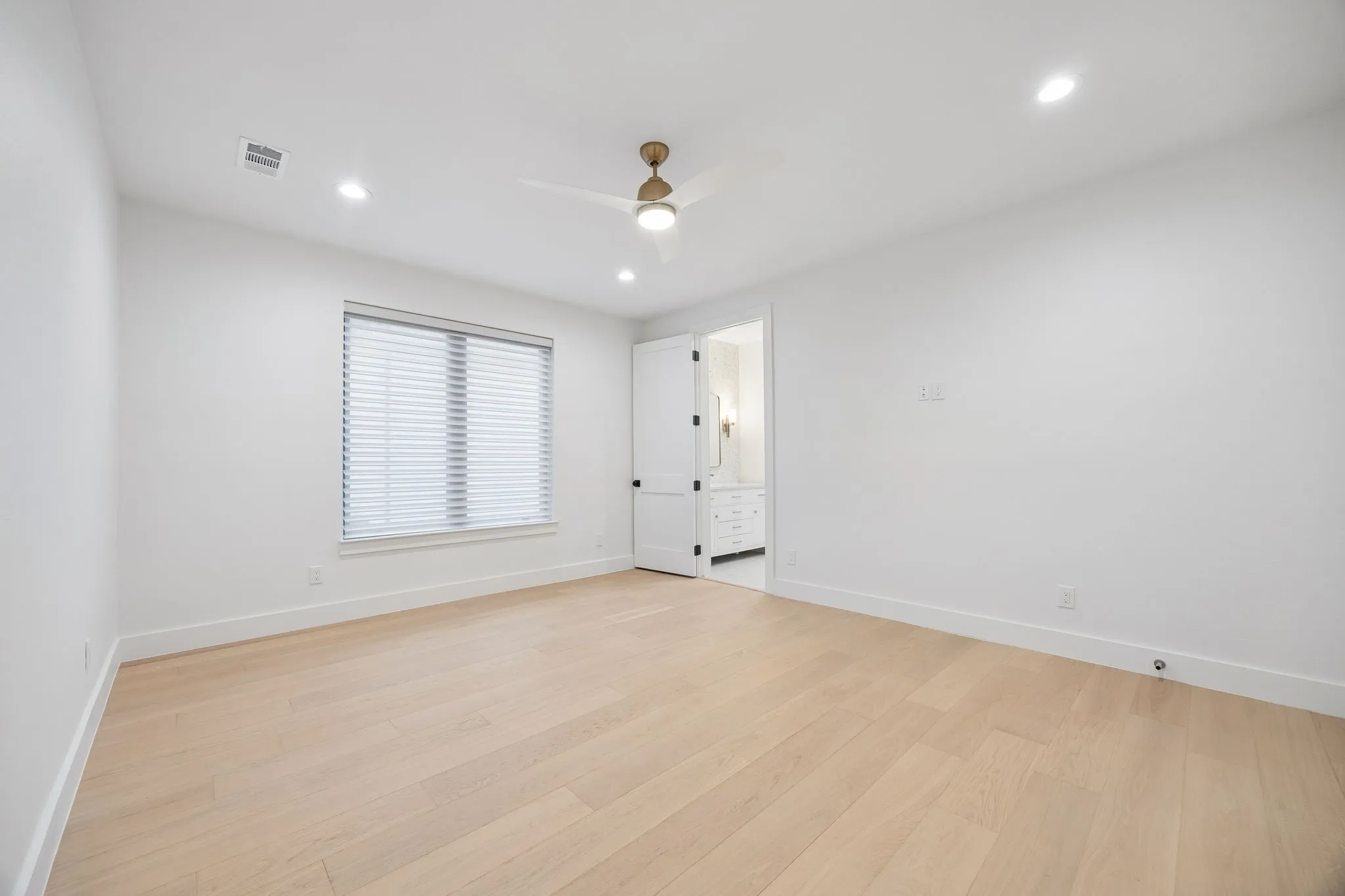 Secondary bedroom with ensuite bath, warm wood floors, and a comfortable, light-filled layout.