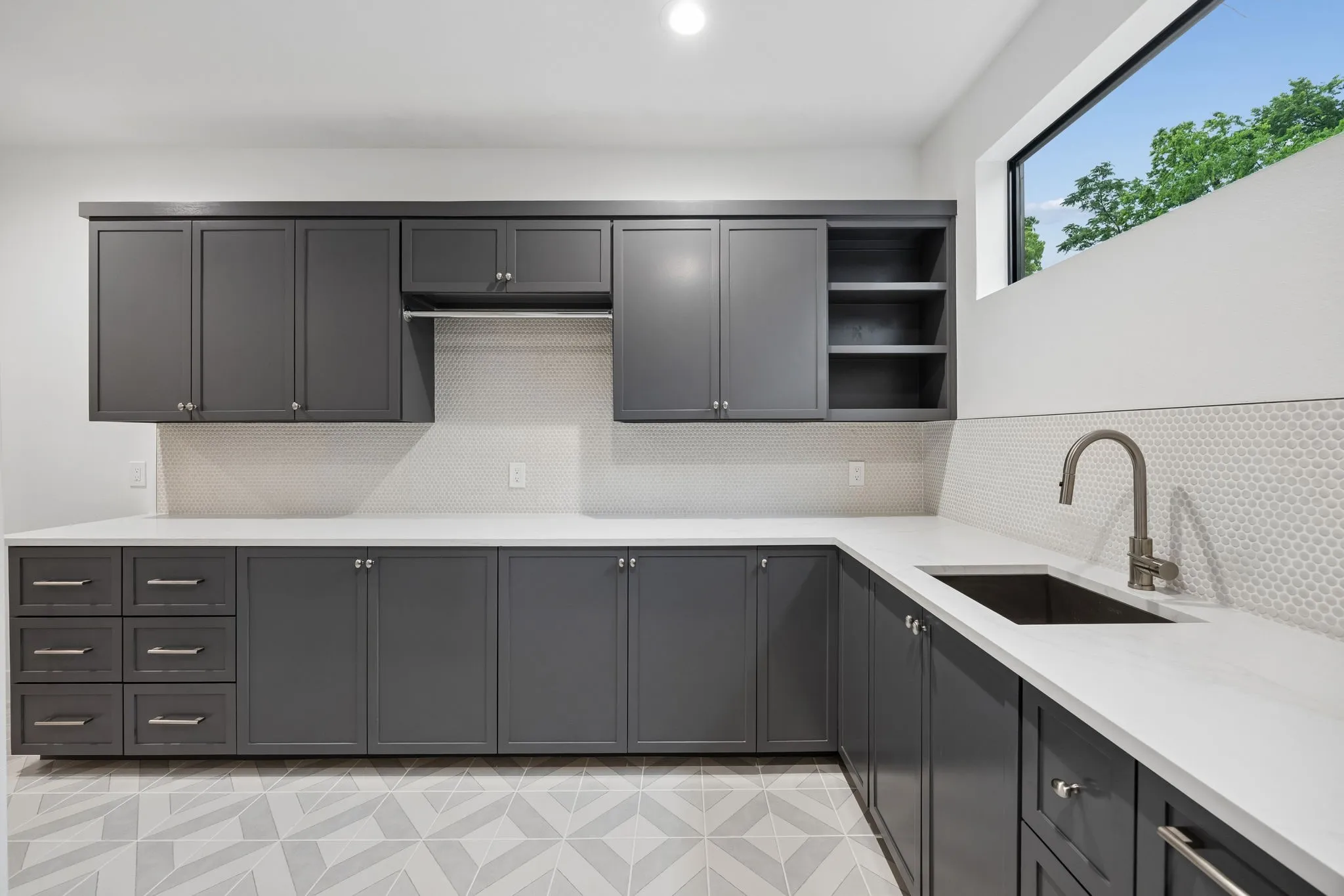 Well-appointed laundry room with extensive cabinetry, sink, and ample counter space for added functionality.