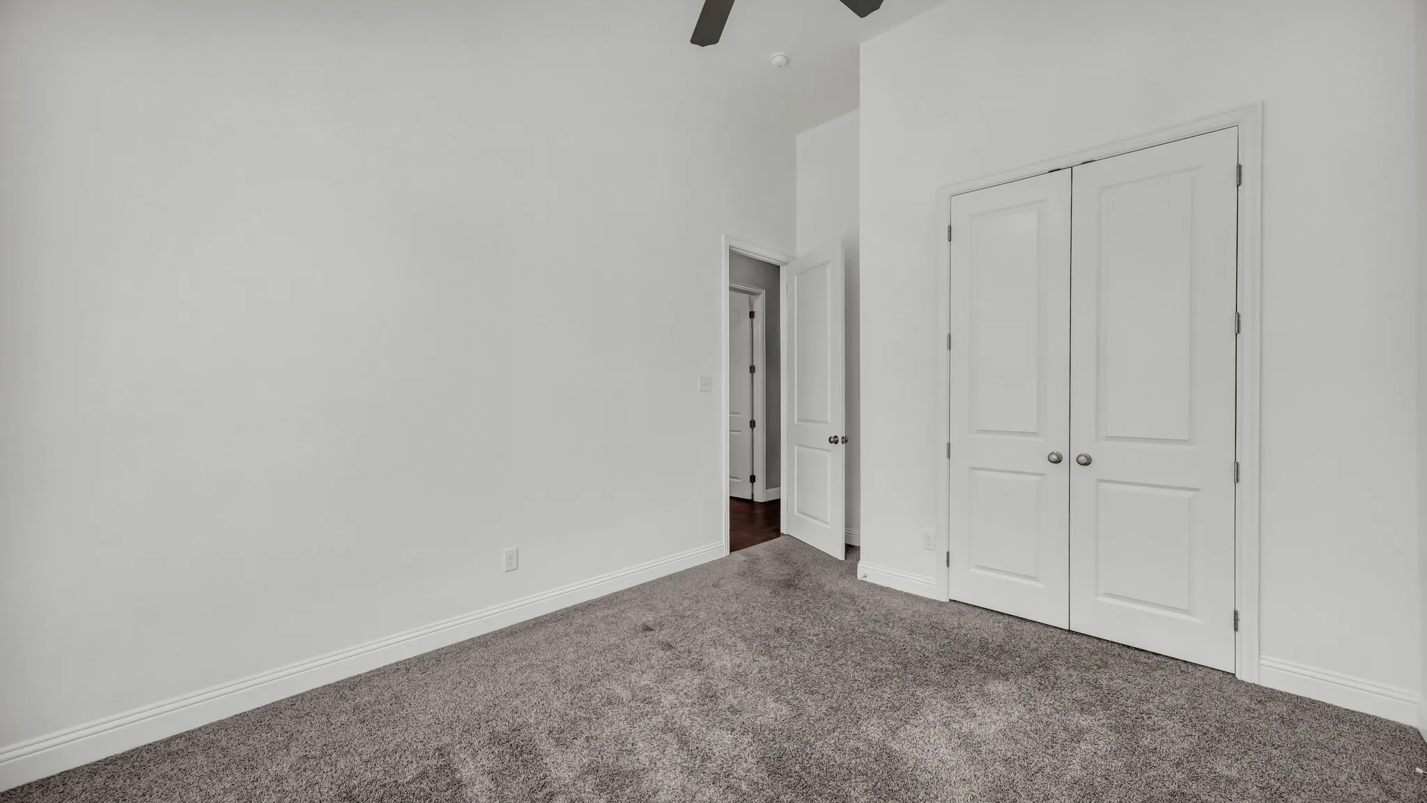 Unfurnished bedroom with carpet flooring, a closet, ceiling fan, and a high ceiling