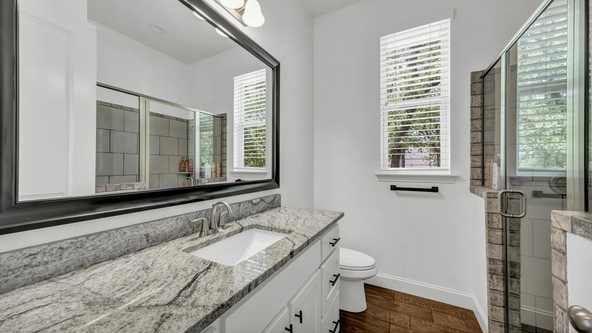 Full bathroom featuring a shower stall, vanity, and dark wood finished floors