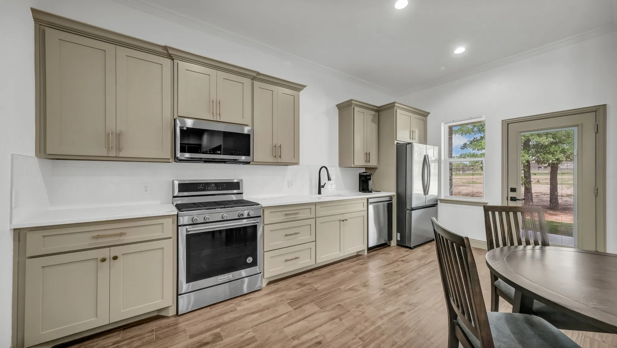 Kitchen with stainless steel appliances, ornamental molding, cream cabinets, light wood-type flooring, and recessed lighting