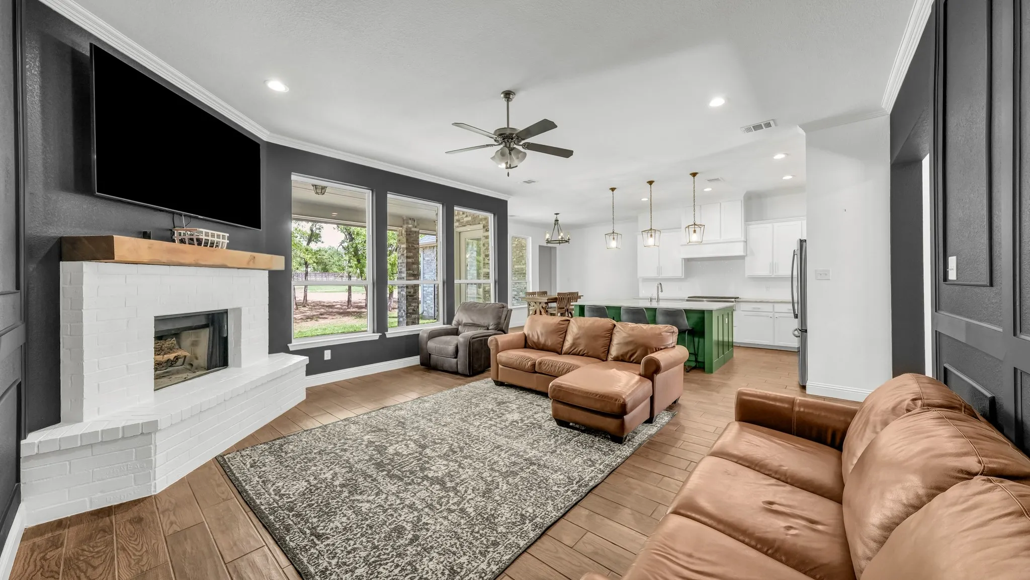 Living area with a brick fireplace, ornamental molding, light wood finished floors, ceiling fan, and recessed lighting