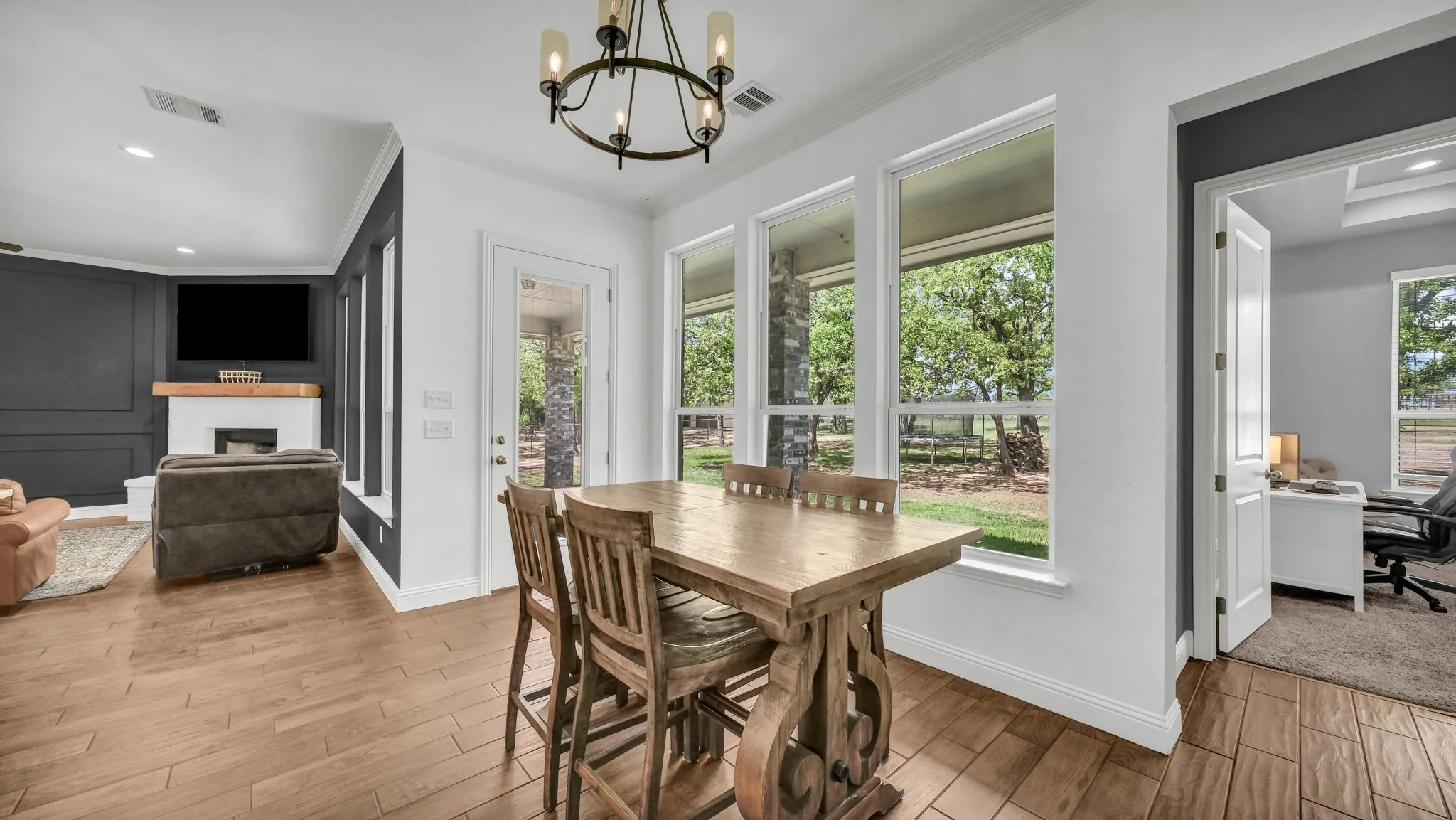 Dining area featuring a desk, a fireplace, wood finished floors, suspended lighting, and plenty of natural light