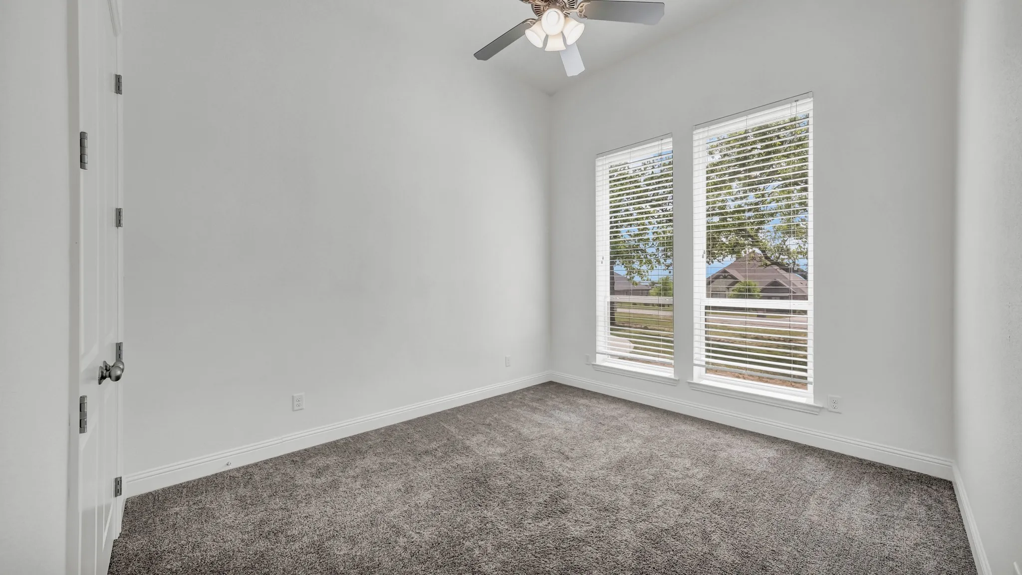 Carpeted empty room with a ceiling fan and baseboards