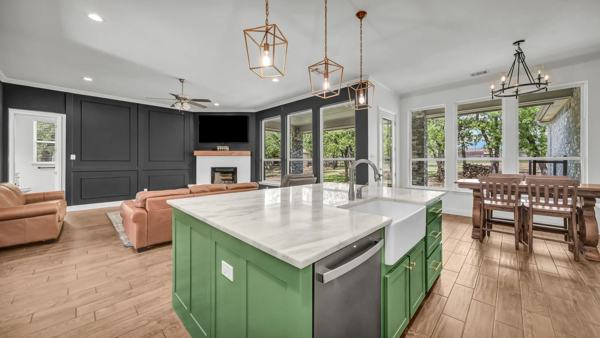 Kitchen featuring green cabinetry, open floor plan, dishwasher, light wood-style flooring, and ornamental molding