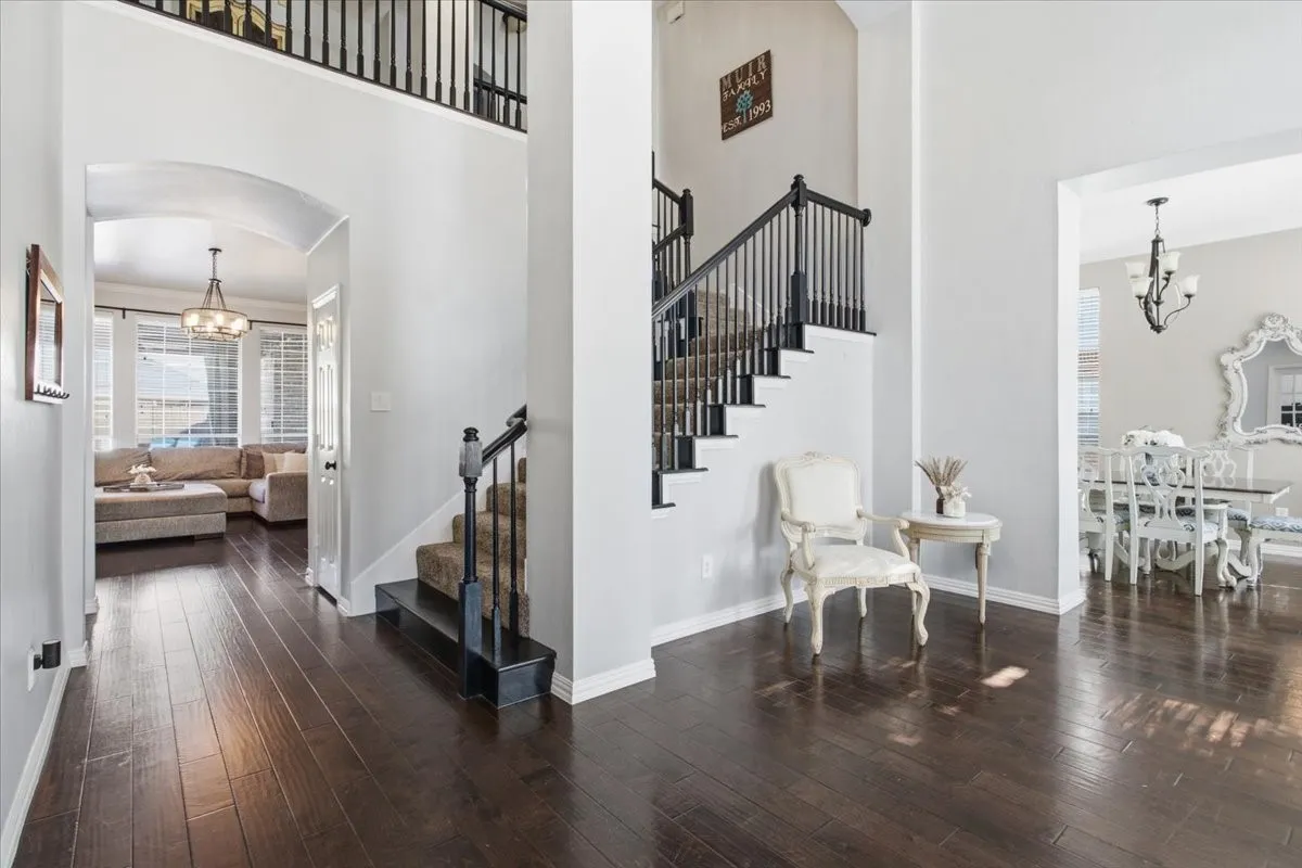 Dark wood-finish flooring throughout the entry, staircase with black balusters, and a second-story open railing