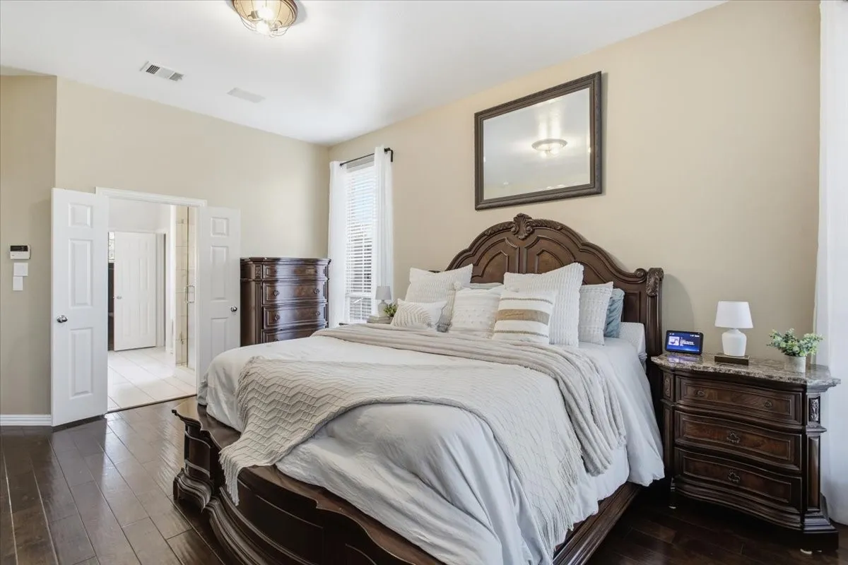 Vaulted ceiling bedroom featuring wood-finish flooring and ample natural light