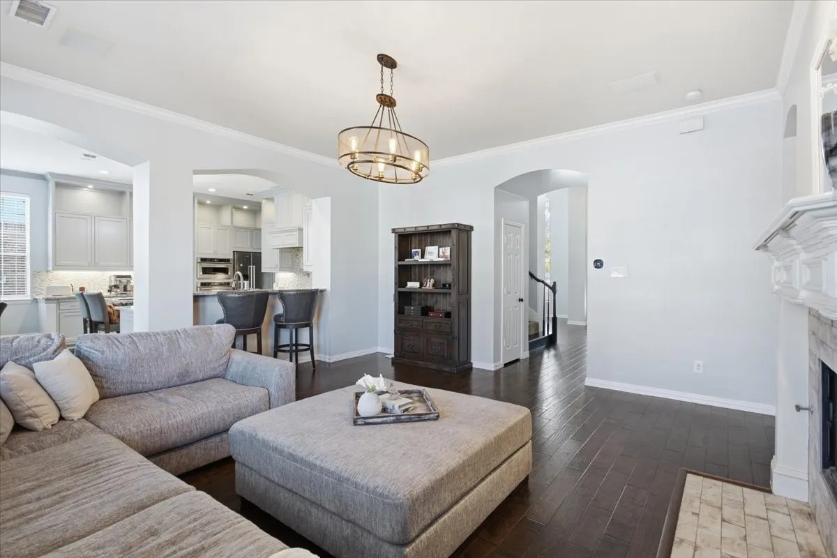 Wood-finish flooring throughout, featuring a fireplace with a detailed mantel, crown molding, and a built-in shelving unit