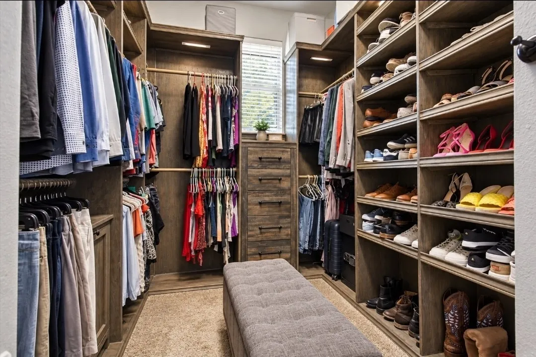 Custom closet system with wood-finish shelving, built-in drawers, multiple hanging rods, and integrated lighting