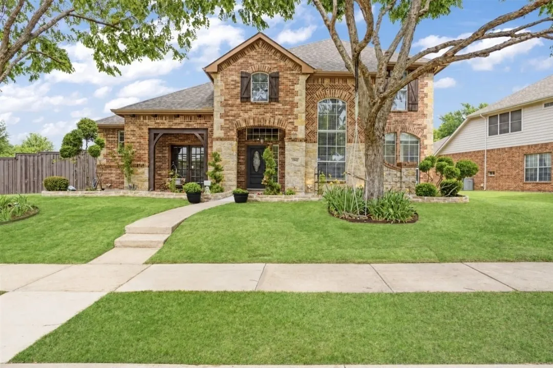 Brick and stone facade residence featuring an arched entry, decorative window shutters, and a covered porch with exposed wood beams