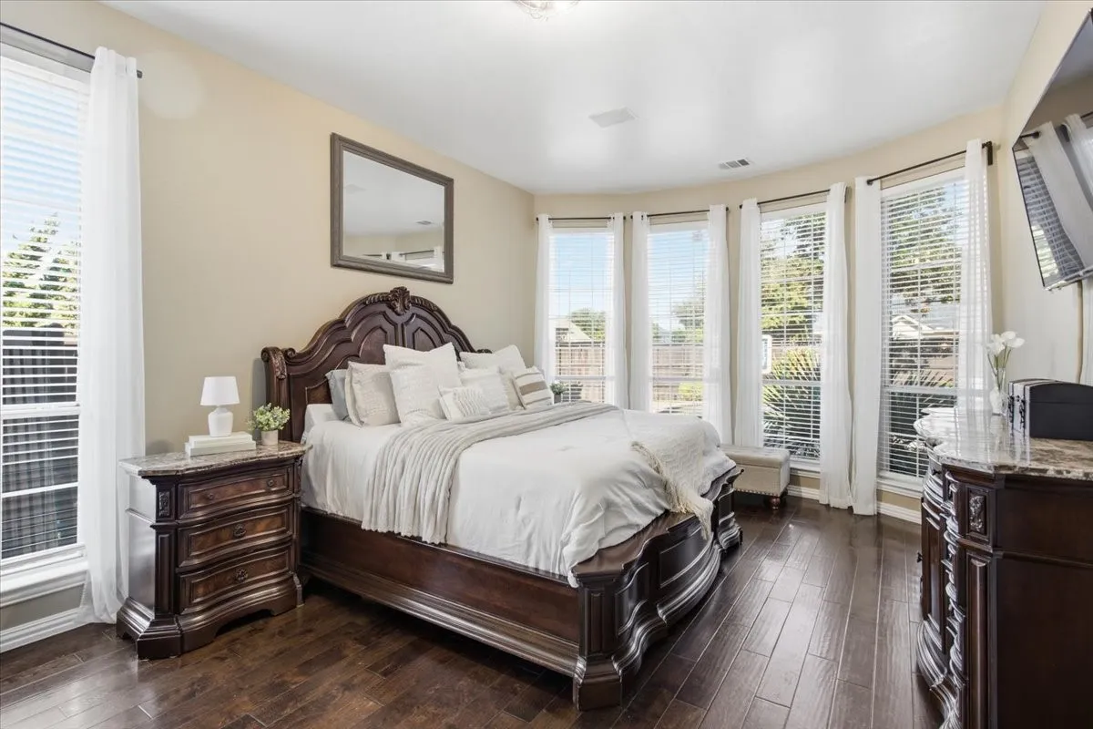 Wood-finish flooring throughout, featuring a bay window with multiple paneled windows, and recessed lighting