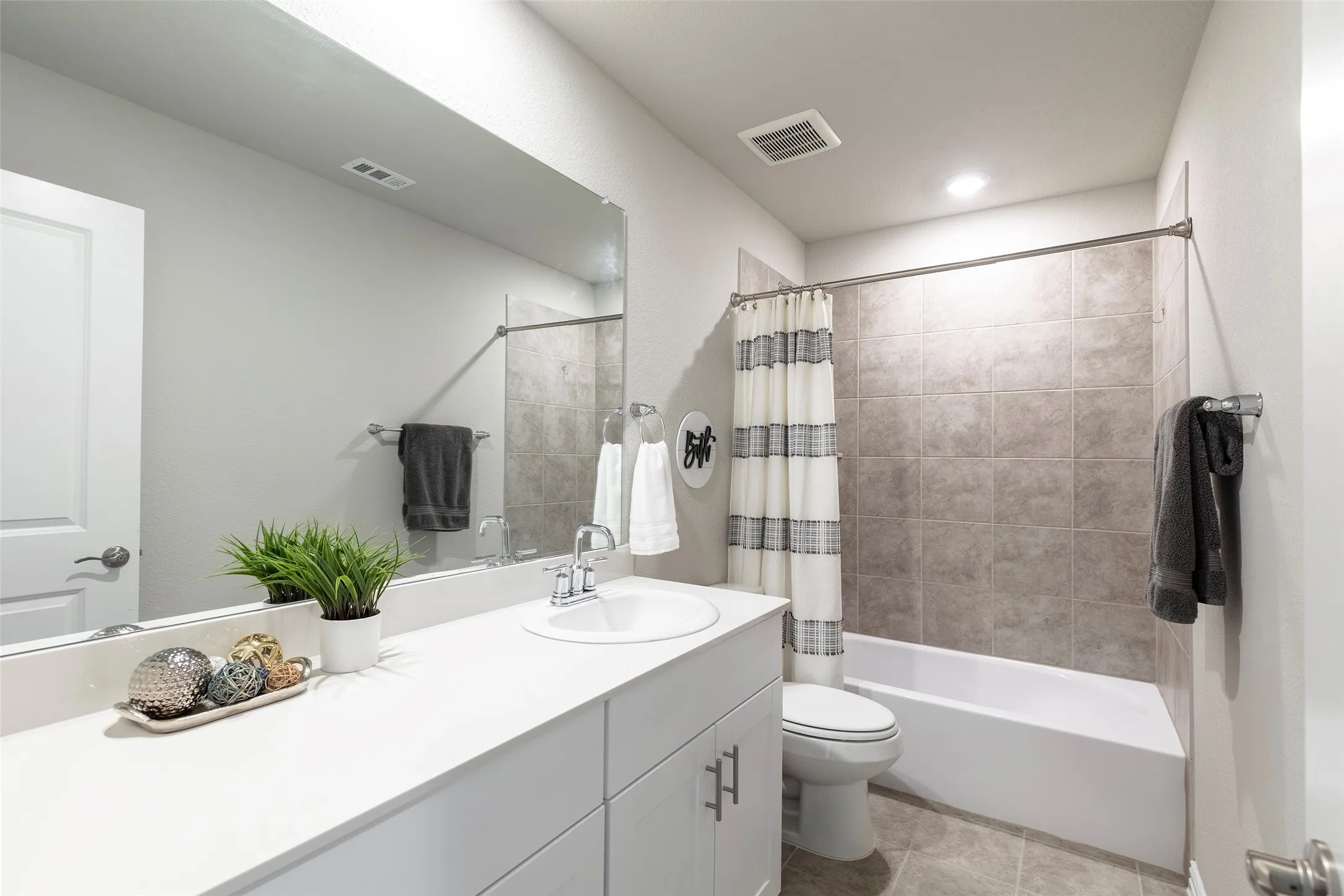 Well-appointed full bath with extended vanity and tiled shower surround.