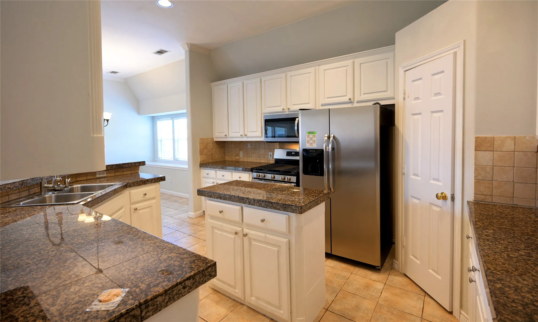 Kitchen featuring white cabinetry, granite countertops, stainless steel appliances, a tiled backsplash, and ceramic tile flooring
