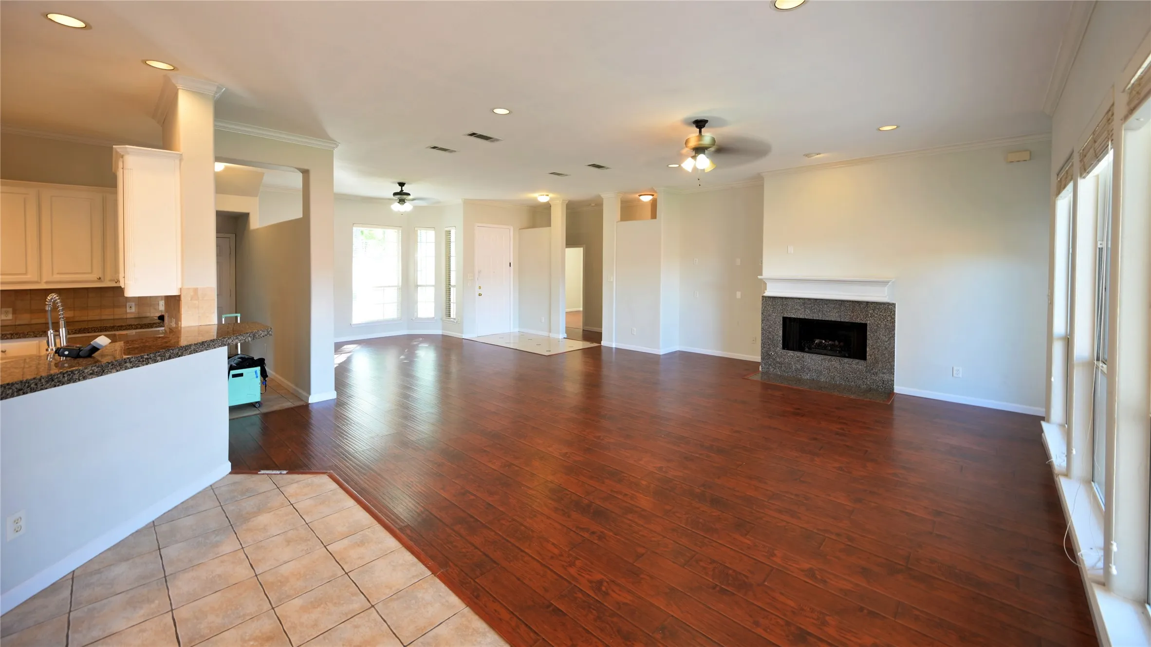 Expansive interior featuring wood-finish flooring, a fireplace with a stone surround, and multiple large windows