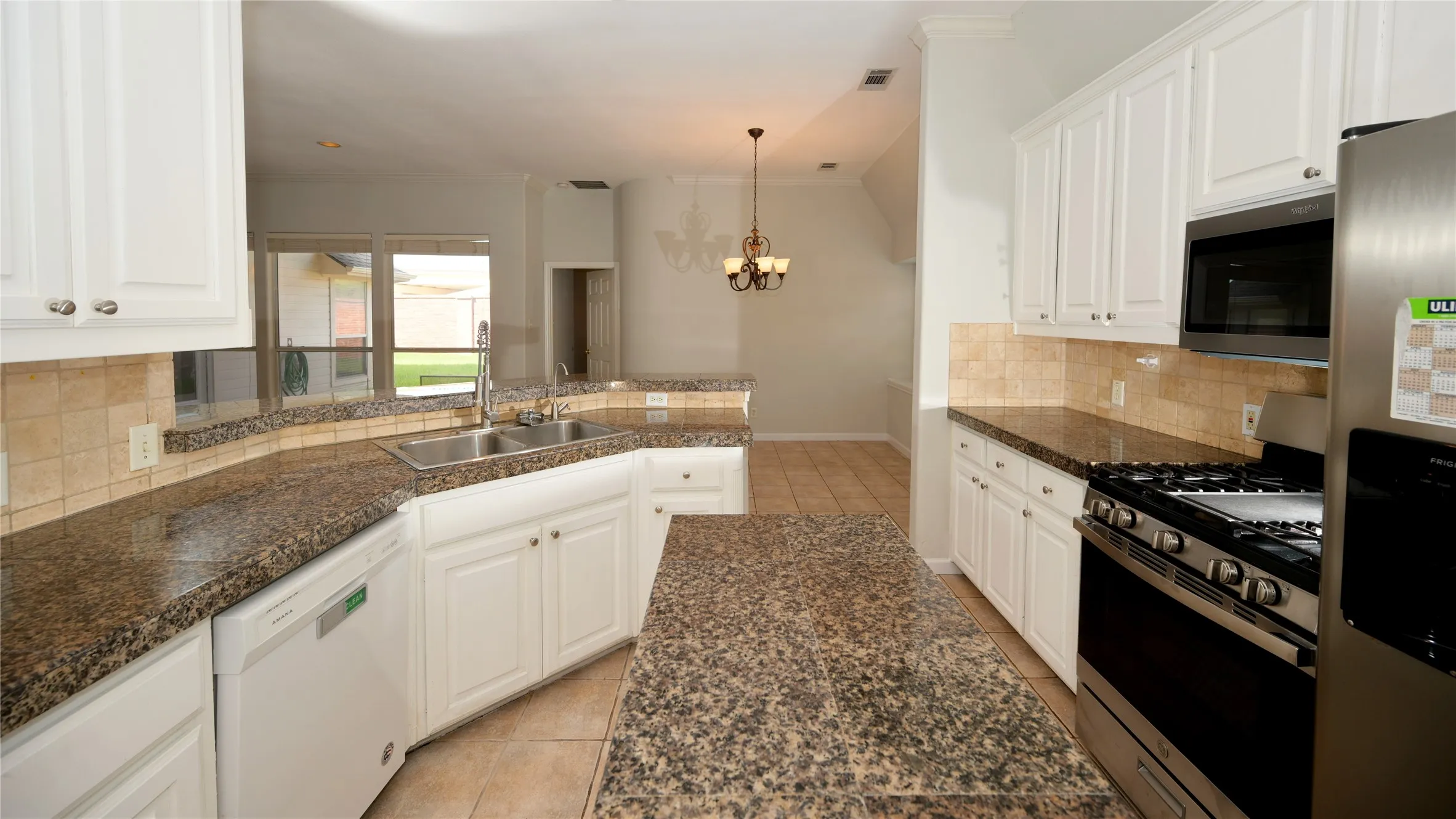 Kitchen featuring white cabinetry, granite countertops, stainless steel appliances, a tile backsplash, and tile flooring