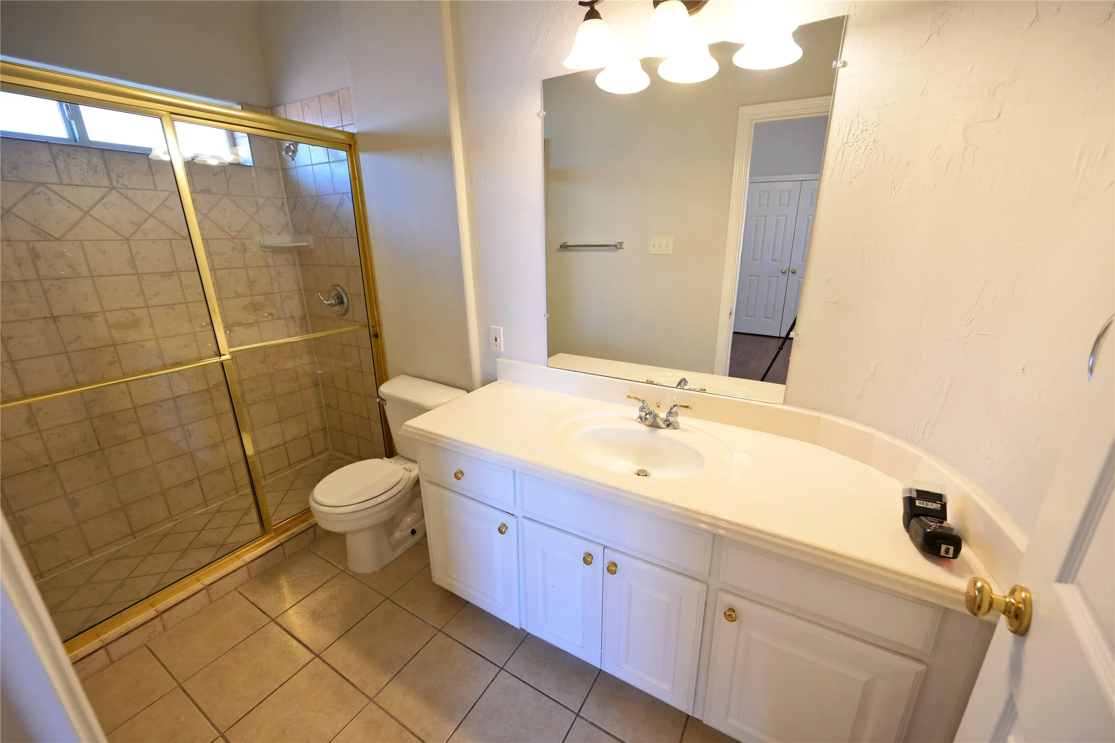 Bathroom featuring a white vanity with an integrated sink, a large mirror, and a three-light fixture