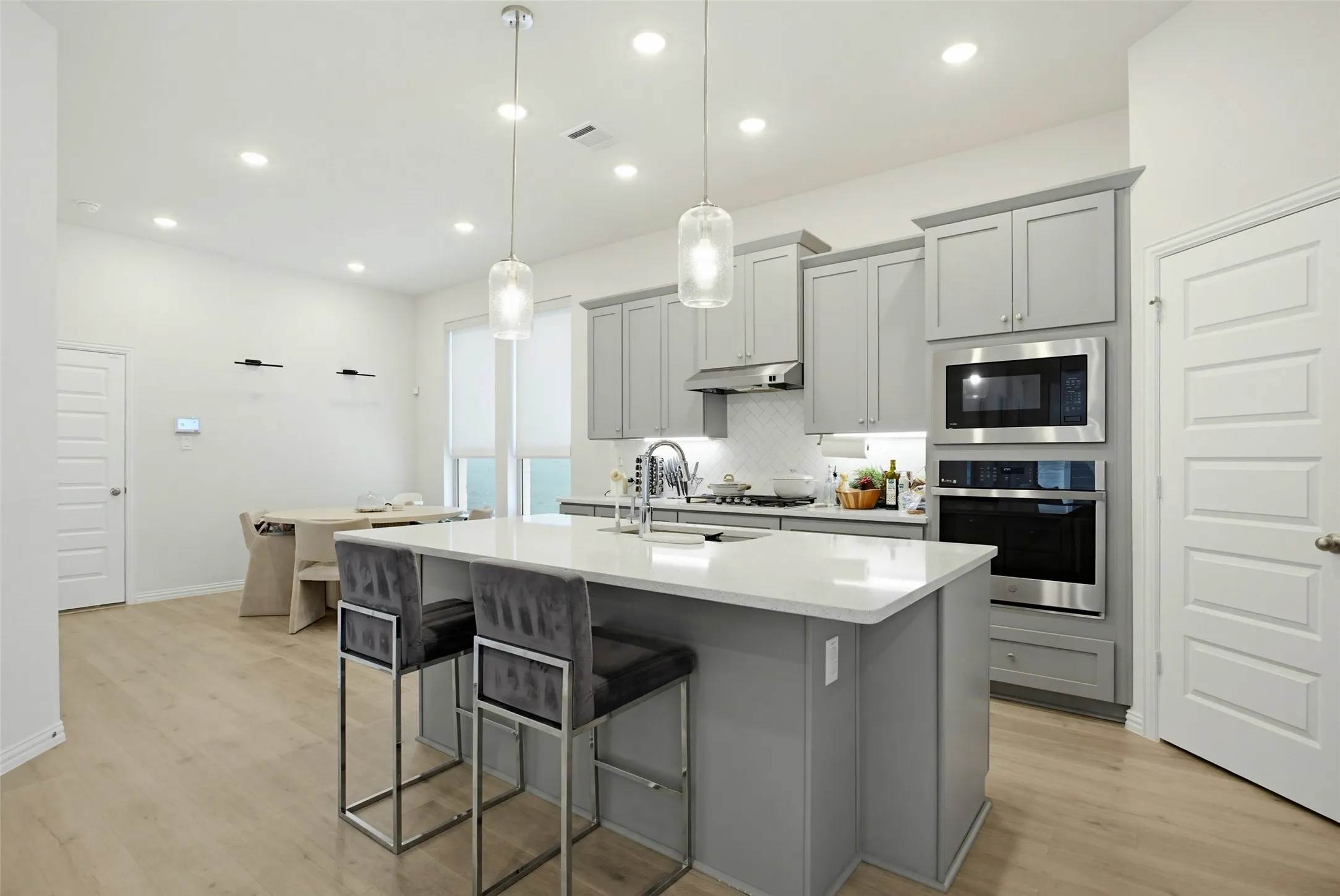 Kitchen with light gray cabinetry, stainless steel appliances, and a white subway tile backsplash