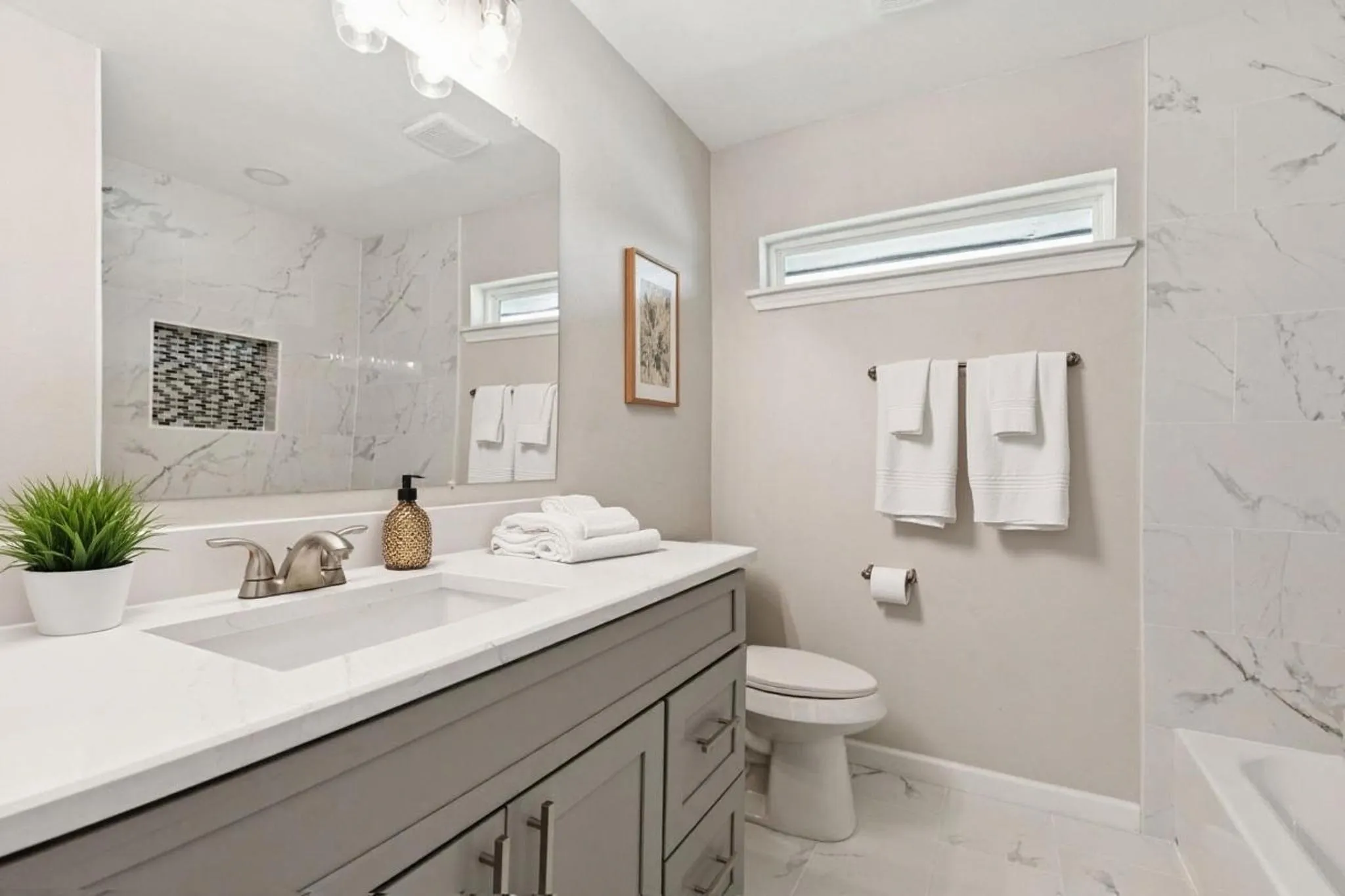 Bathroom featuring vanity, light marble finish floors, and shower / bathtub combination