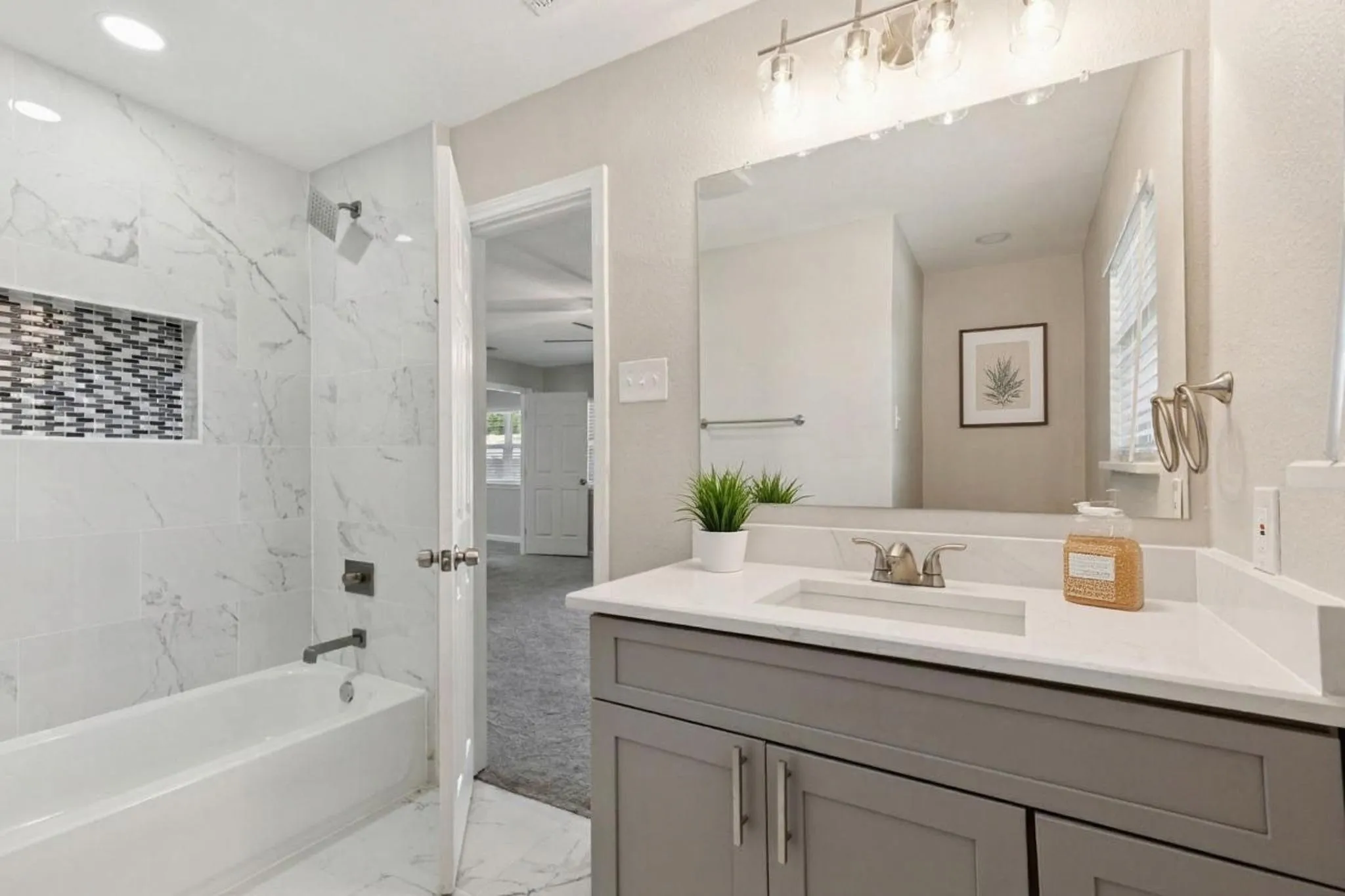 Bathroom with vanity, tub / shower combination, and light marble finish floors